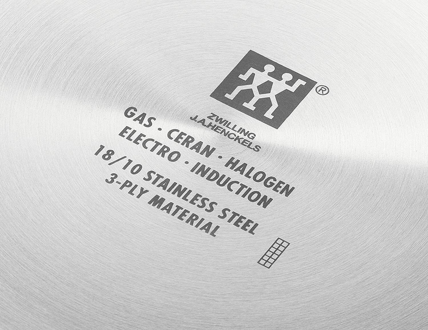 Unterseite eines Woks mit Zwilling-Logo und Infos zu Edelstahl, 3-Schicht-Material und Herdarten, frontal fotografiert.