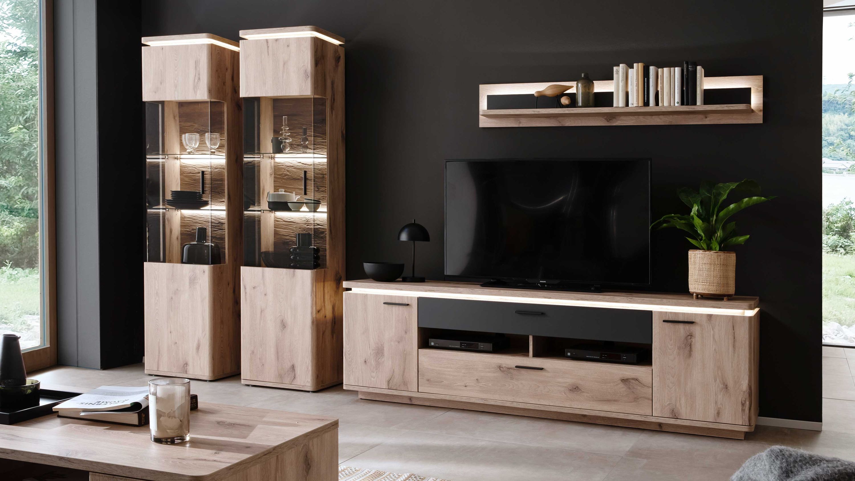 Vierteilige Wohnwand aus hellem Holz mit zwei Vitrinenschränken TV-Board und Wandregal mit Beleuchtung