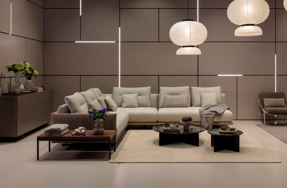 Großes beiges Ecksofa mit weichen Polstern und Zierkissen, kombiniert mit runden Designer-Couchtischen und dekorativen Pendelleuchten in einem modernen Wohnambiente.