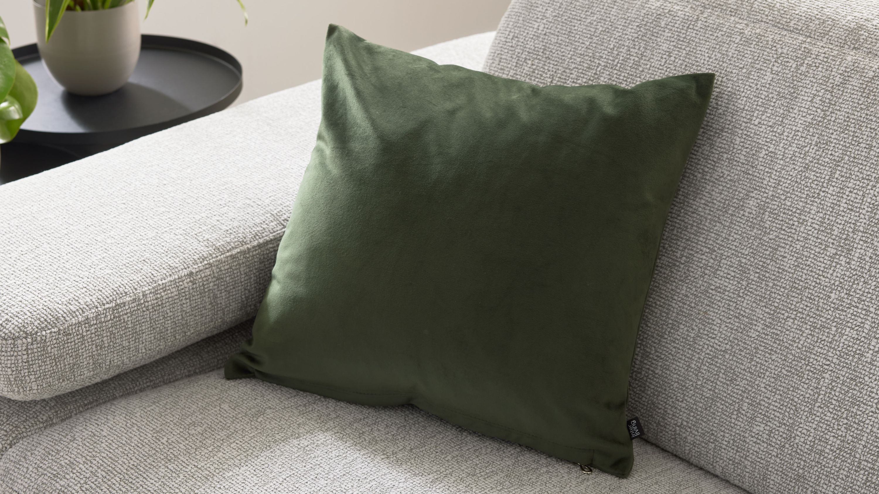 Quadratische Kissenhülle in olivgrün auf hellgrauem Sofa