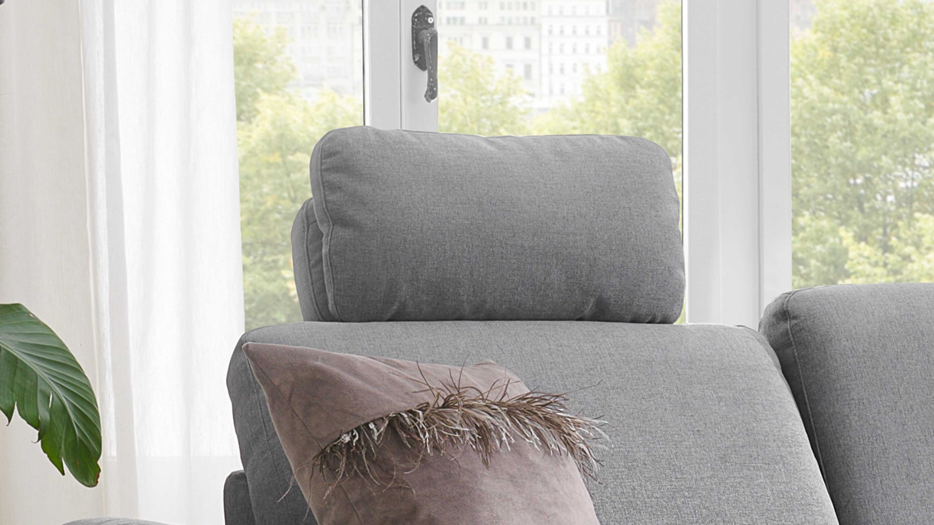 Sofateil mit multifunktionaler Kopfstütze in Platingrau Sofateil mit multifunktionaler Kopfstütze und platingrauem Bezug vor Fenster mit grünen Bäumen