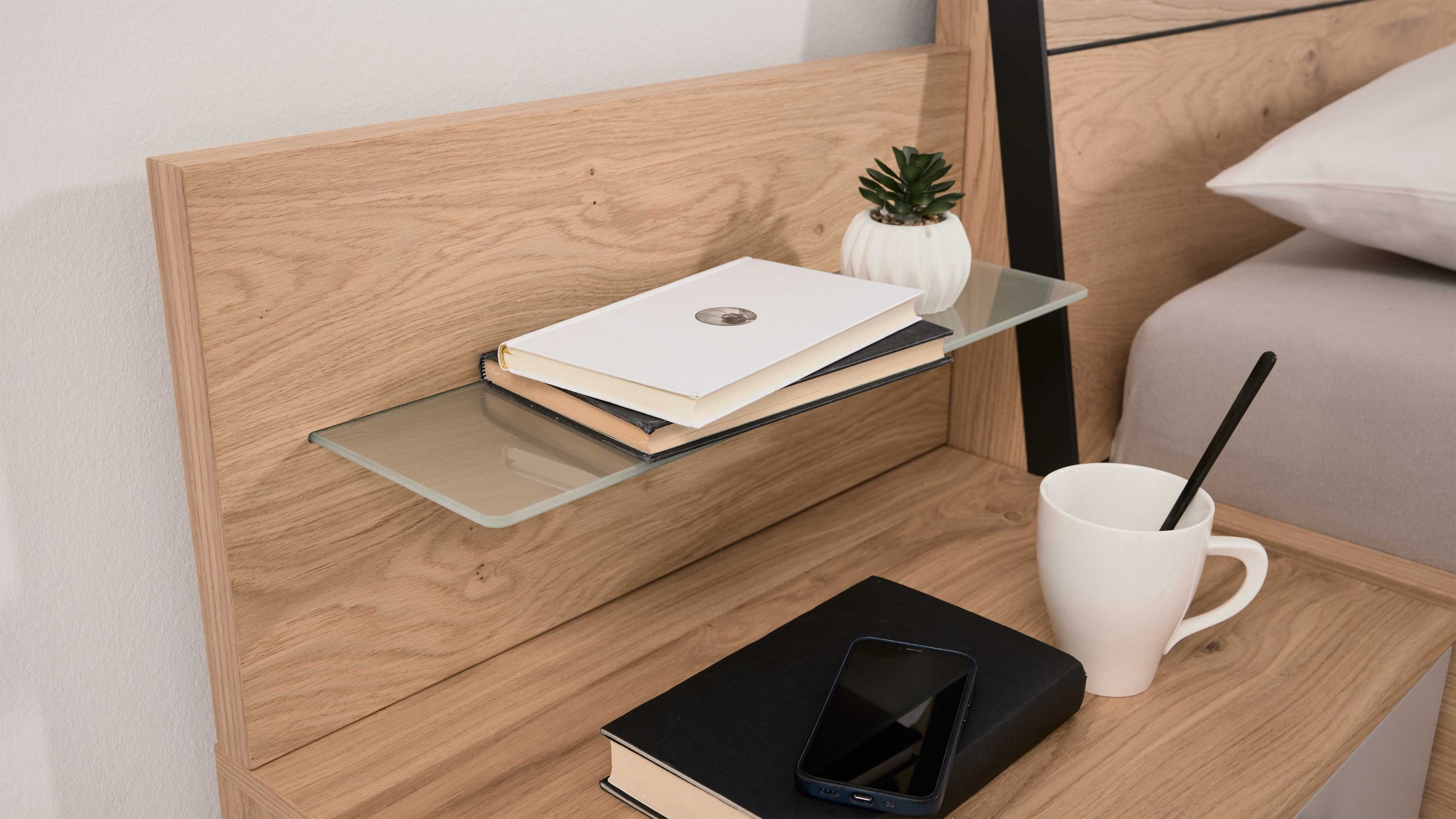 Paneelaufsatz aus Holz mit Glasablage und Dekoration neben einem Bett