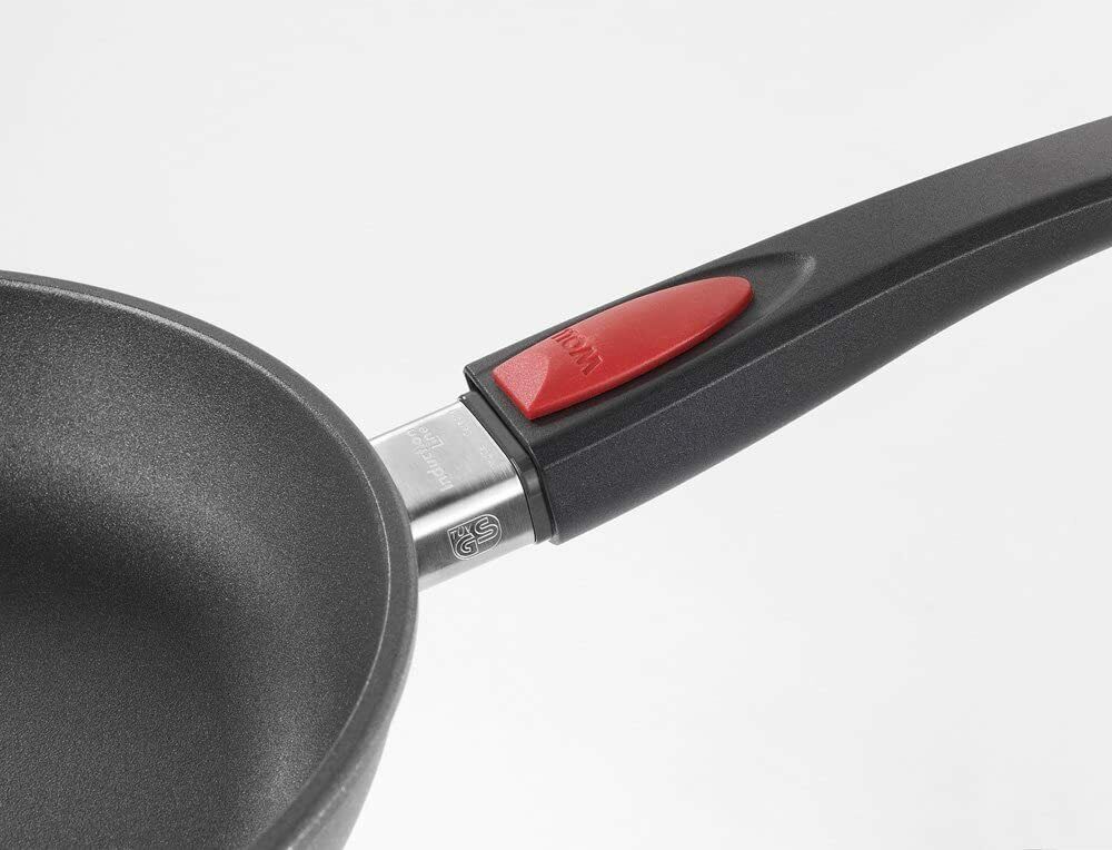 Schwarze Pfanne mit langem Griff, roter Knopf am Griffansatz, Nahaufnahme aus schräger Perspektive