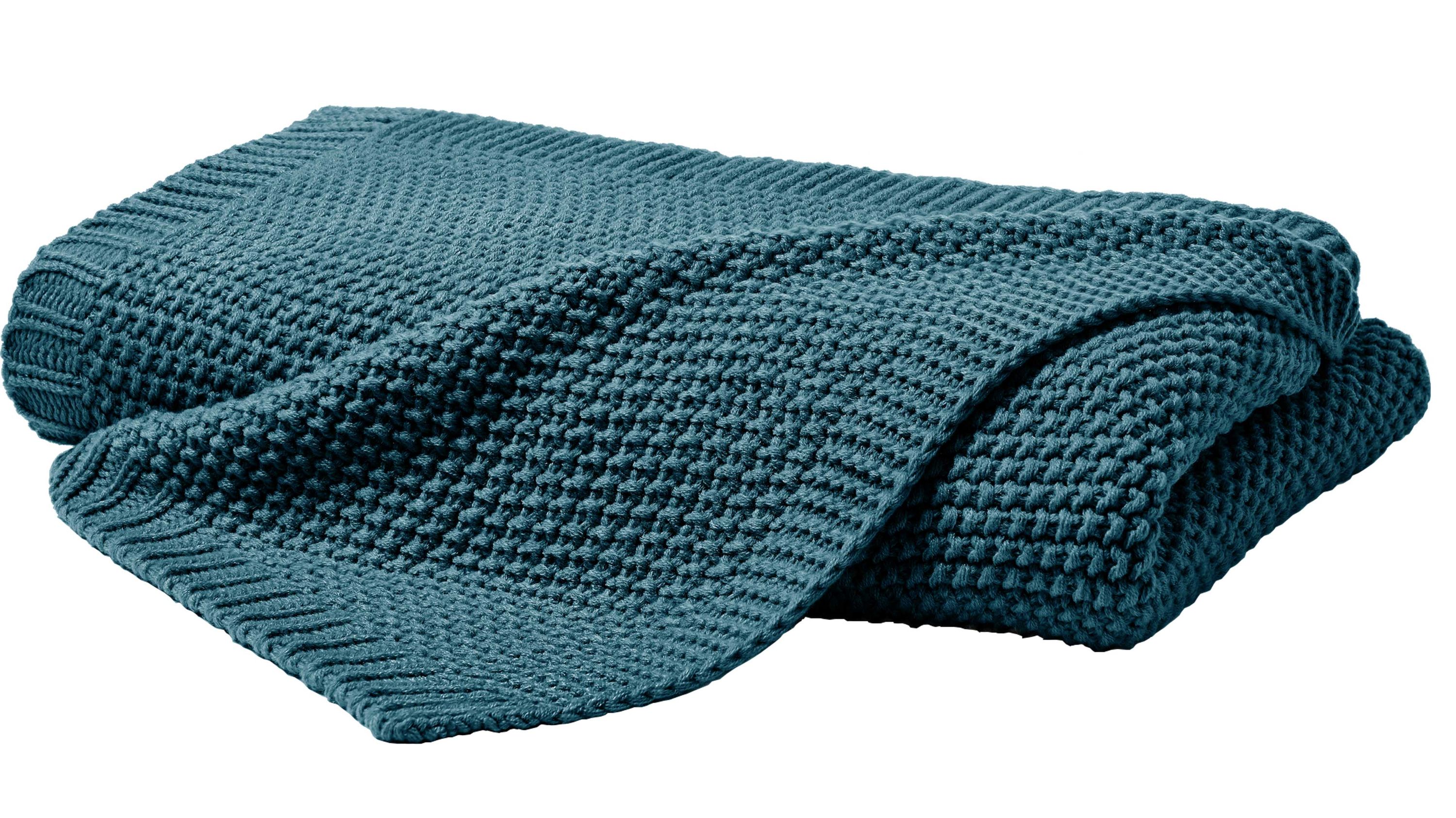 Gefaltete Strickdecke mit strukturierter Oberfläche in dunkelgrüner Farbe