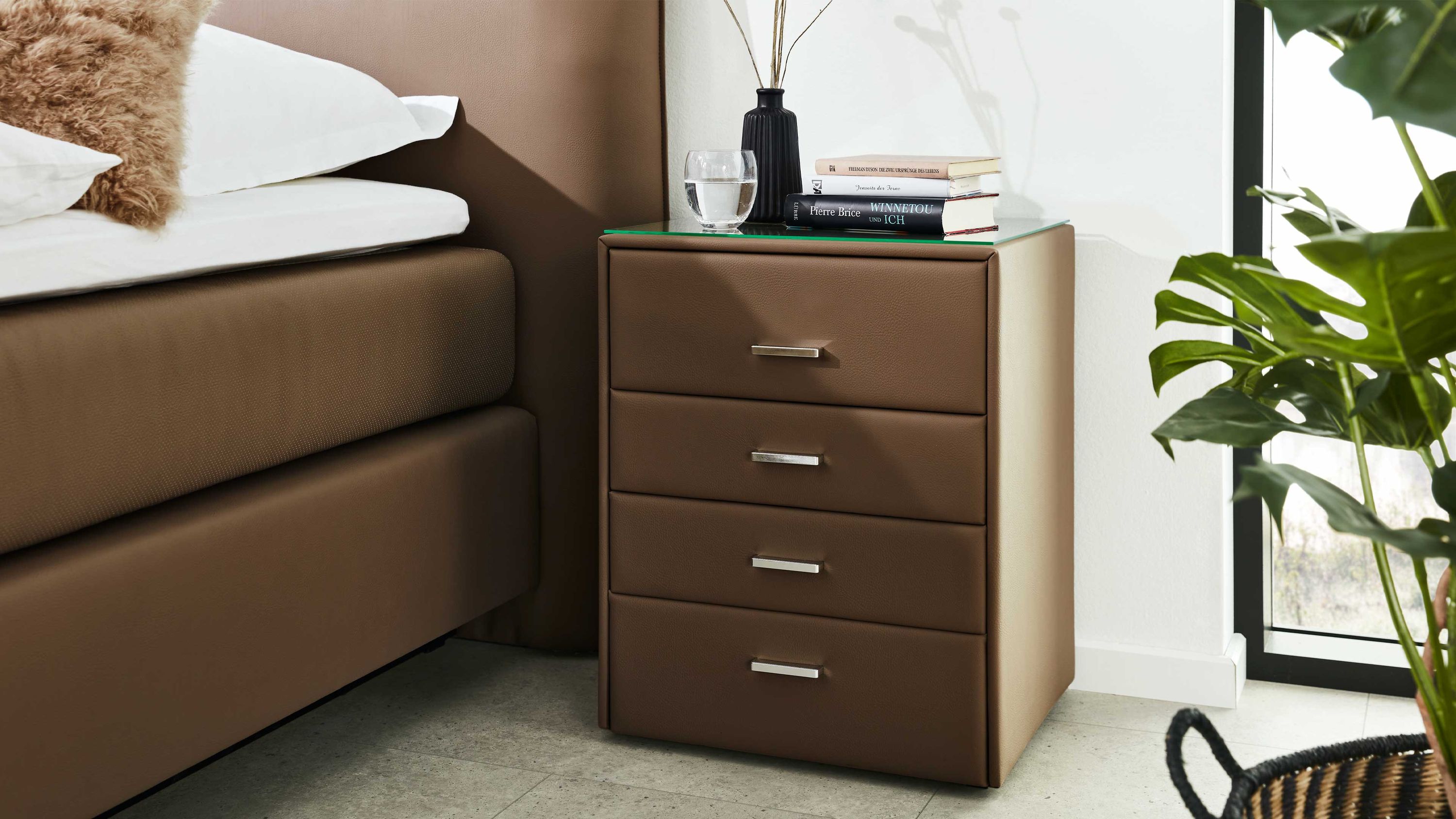 Schlammfarbene Nachtkommode mit vier Schubladen und Metallgriffen neben braunem Boxspringbett