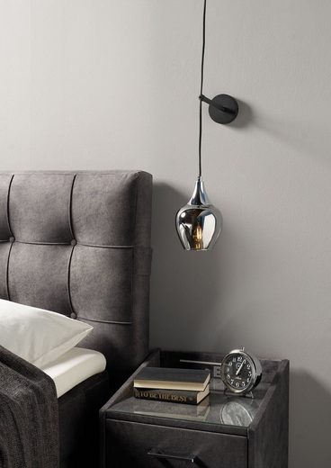 Elegante Pendelleuchte mit Glasschirm und Aluminiumdetail Pendelleuchte mit silbernem Aluminiumabschluss und Glasschirm schräg über Nachttisch gehängt