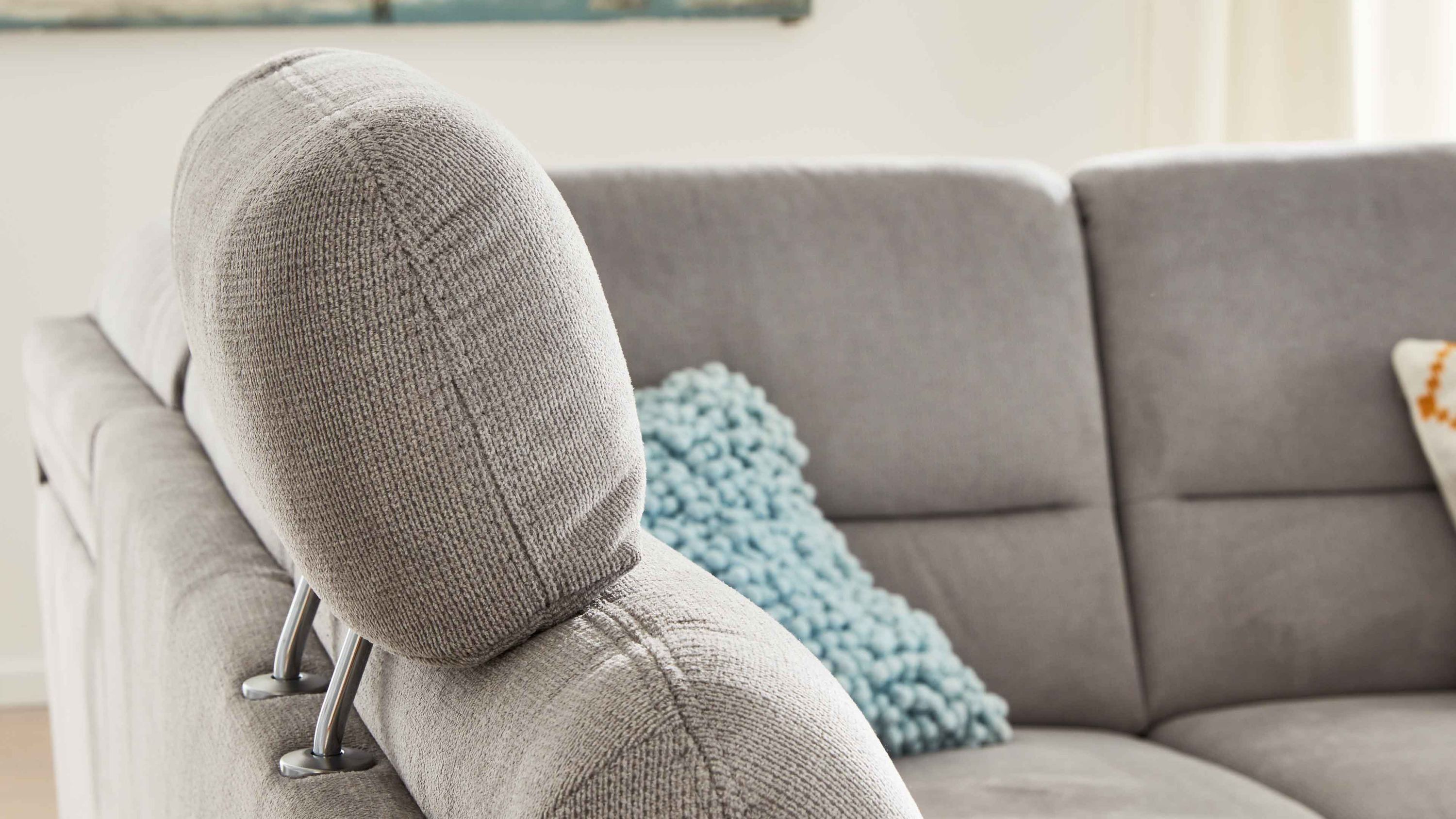 Silberfarbene Kopfstütze aus Chenille auf grauem Sofa mit Metallstangen