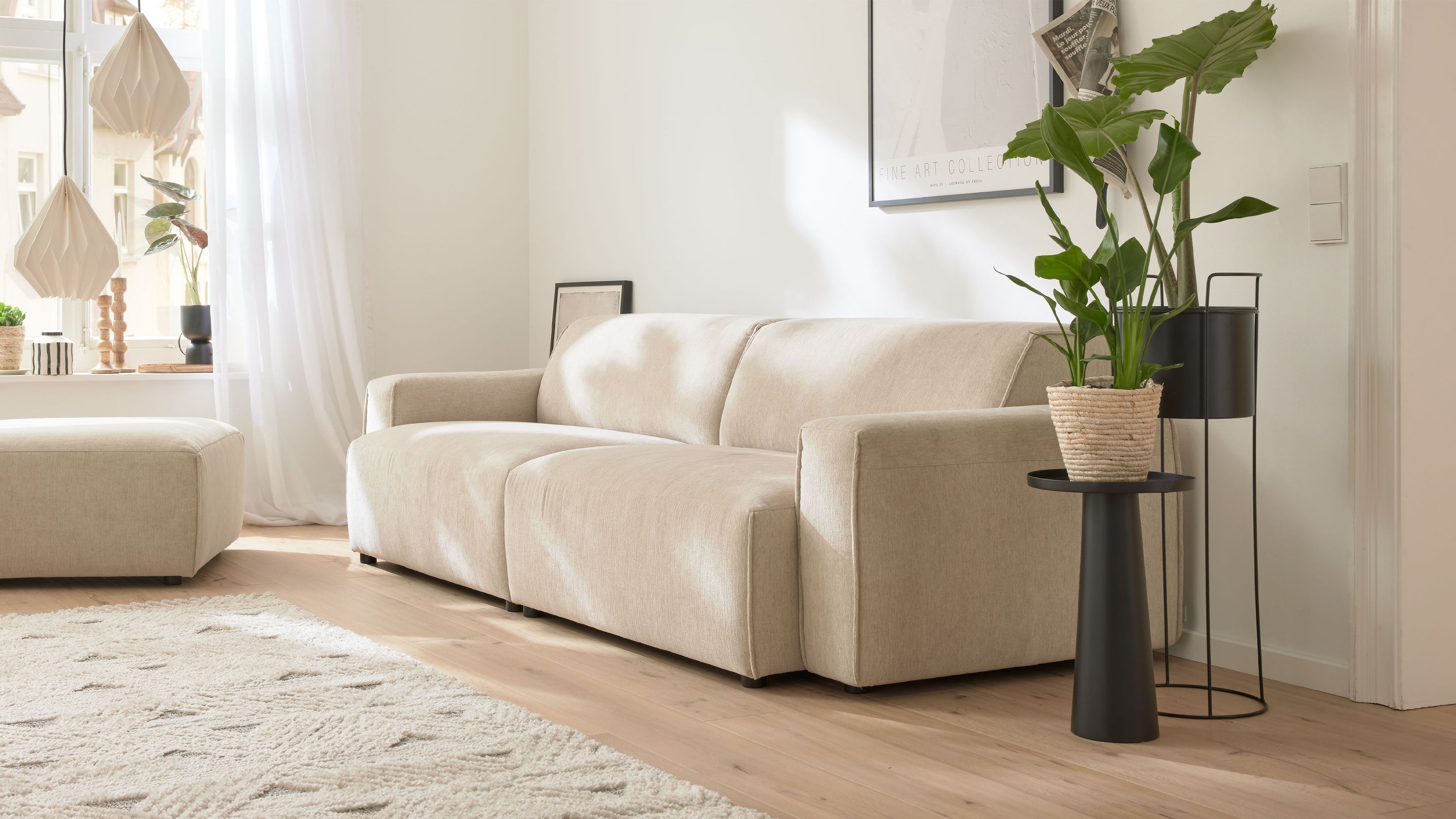 Großes Sofa mit champagnerfarbenem Bezug in modernem Wohnzimmer mit Pflanzen und Teppich