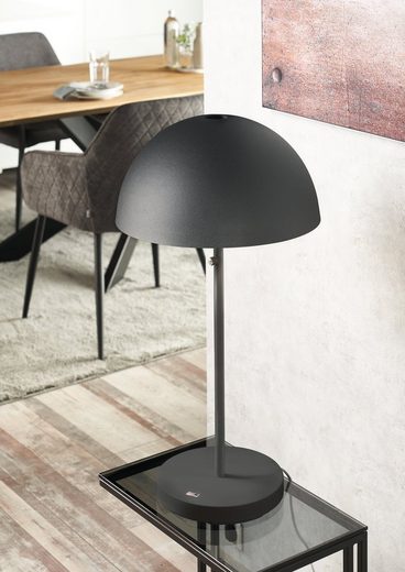 Schwarze Tischlampe mit Kuppelschirm auf Beistelltisch, vor Essbereich, aus seitlicher Perspektive fotografiert