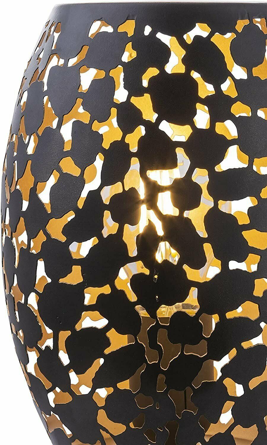 Detailansicht runder Leuchte mit floralem Lochmuster in Schwarz und Gold warm durchleuchtet und seitlich aufgenommen