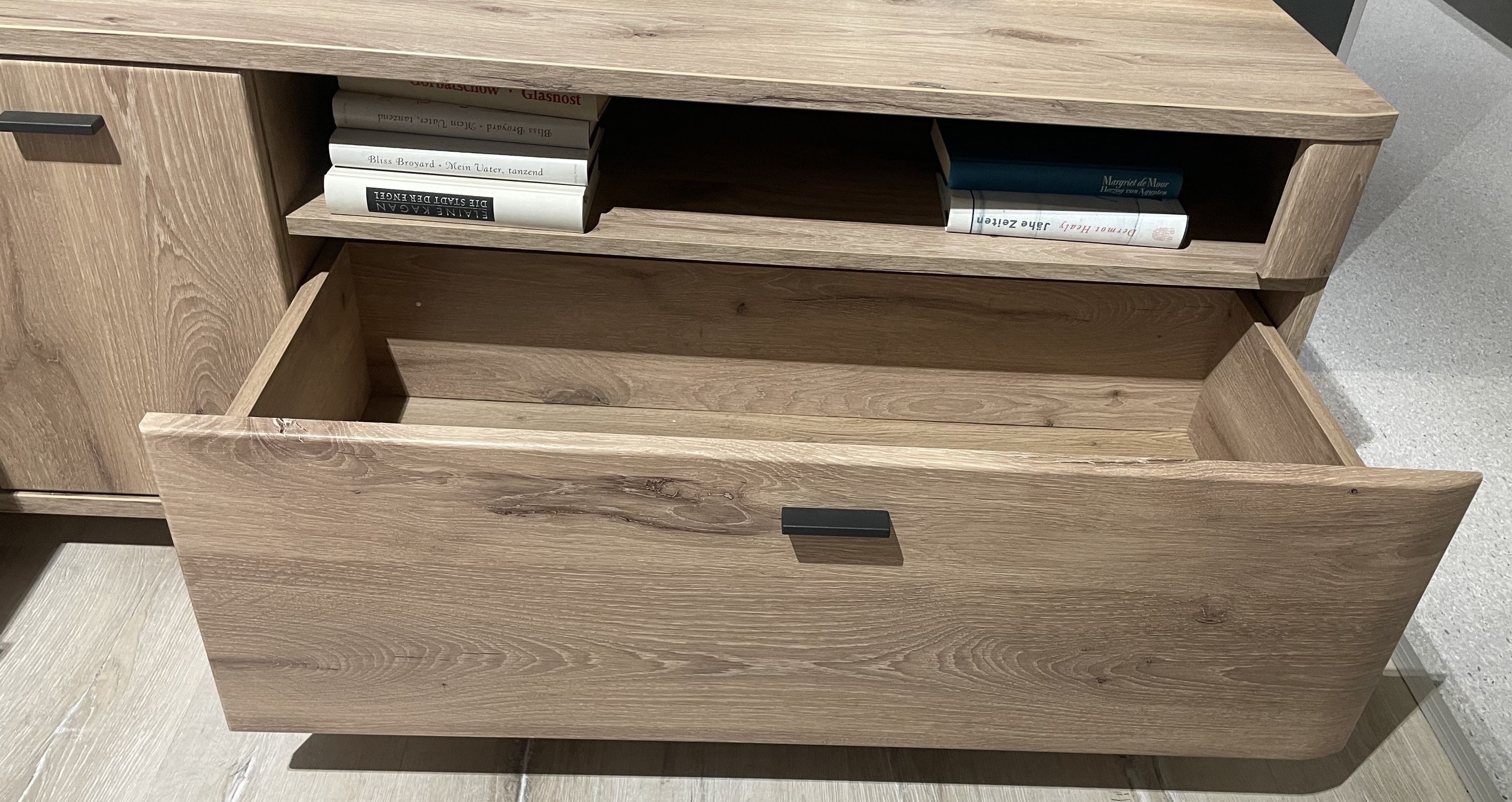 Wohnwand mit offener Ablage und großer Schublade in Holzoptik mit schwarzem Griff