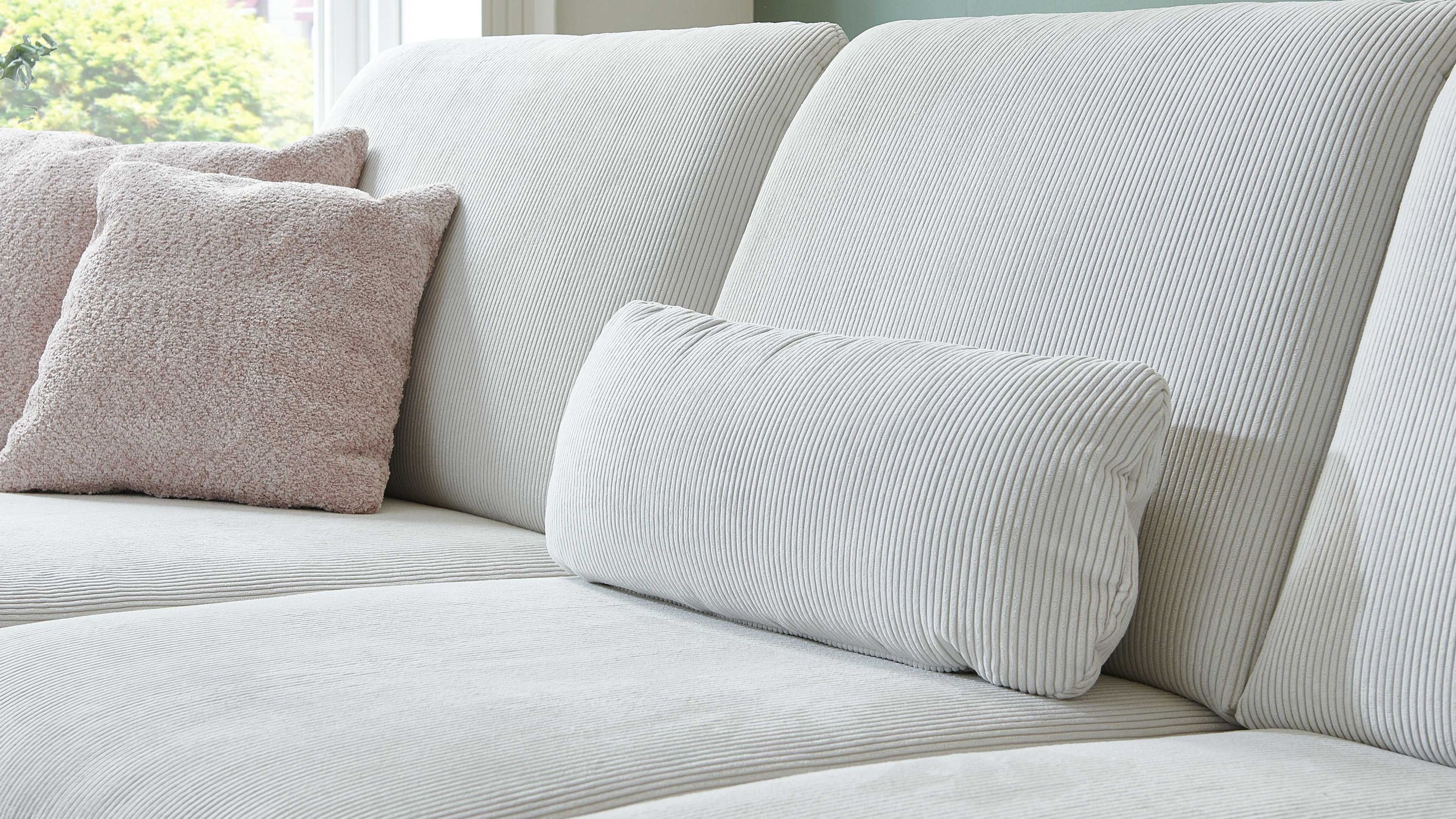 Nierenkissen in naturweiß mit feiner Cordstruktur auf einem hellen Sofa mit weiteren Kissen