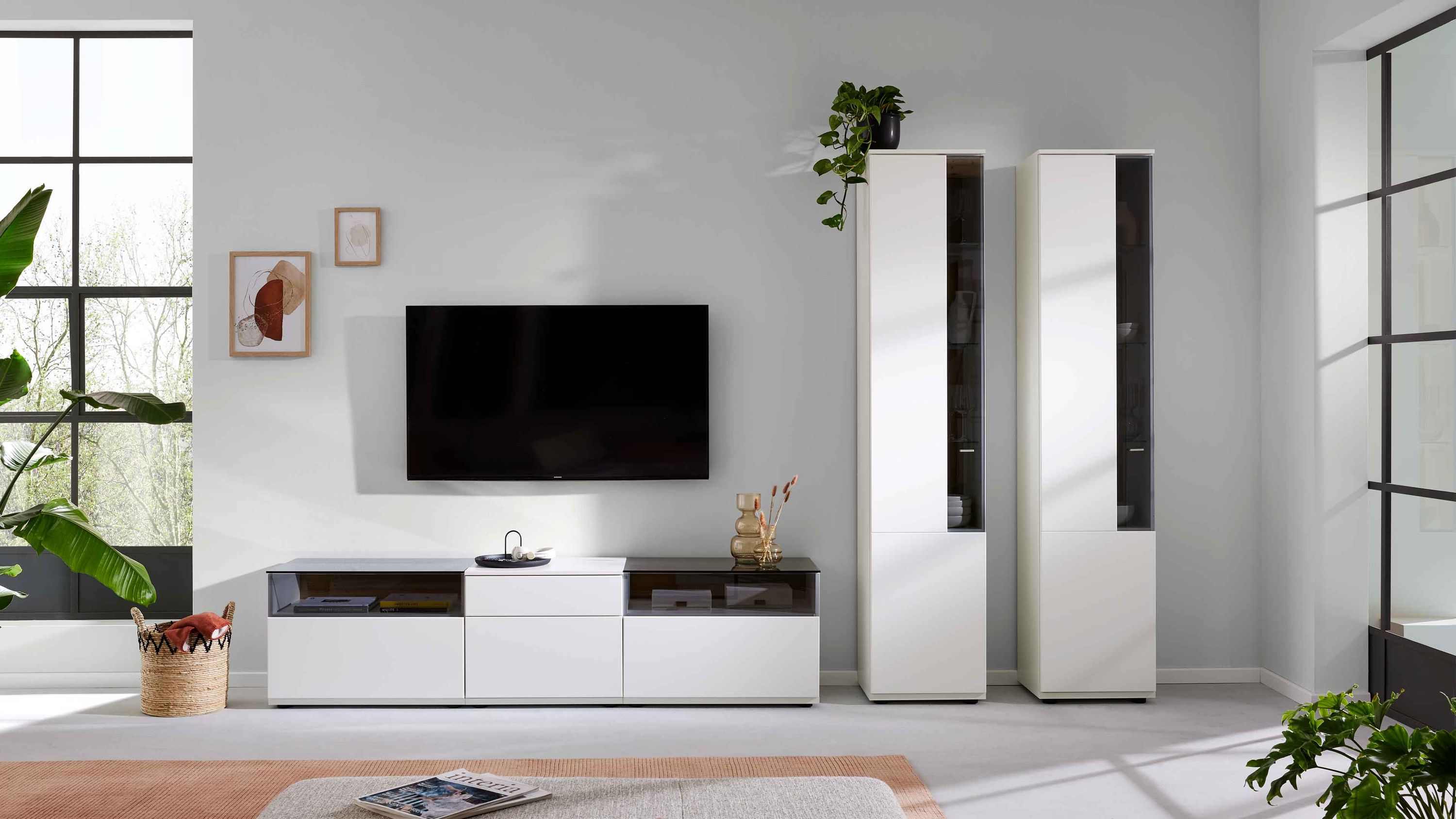 Weiße Wohnwand mit grauen Glasfronten Weiße Wohnwand mit zwei hohen Schränken und einem Lowboard mit grauen Glasfronten in modernem Wohnzimmer