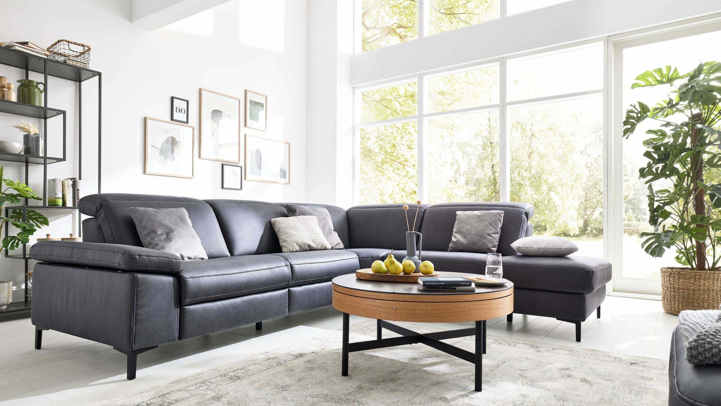 Ecksofa in dunkler Mikrofaser mit verstellbaren Armlehnen und schwarzen Füßen in hellem Wohnzimmer