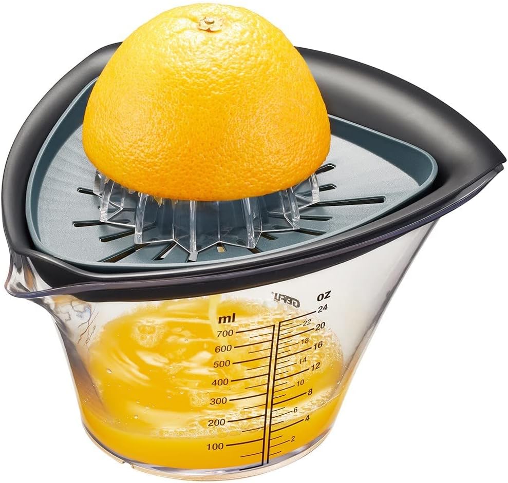 Manuelle Zitruspresse mit schwarzem Presskegel transparenter Schale mit Skala halbierte Orange leicht schräge Ansicht