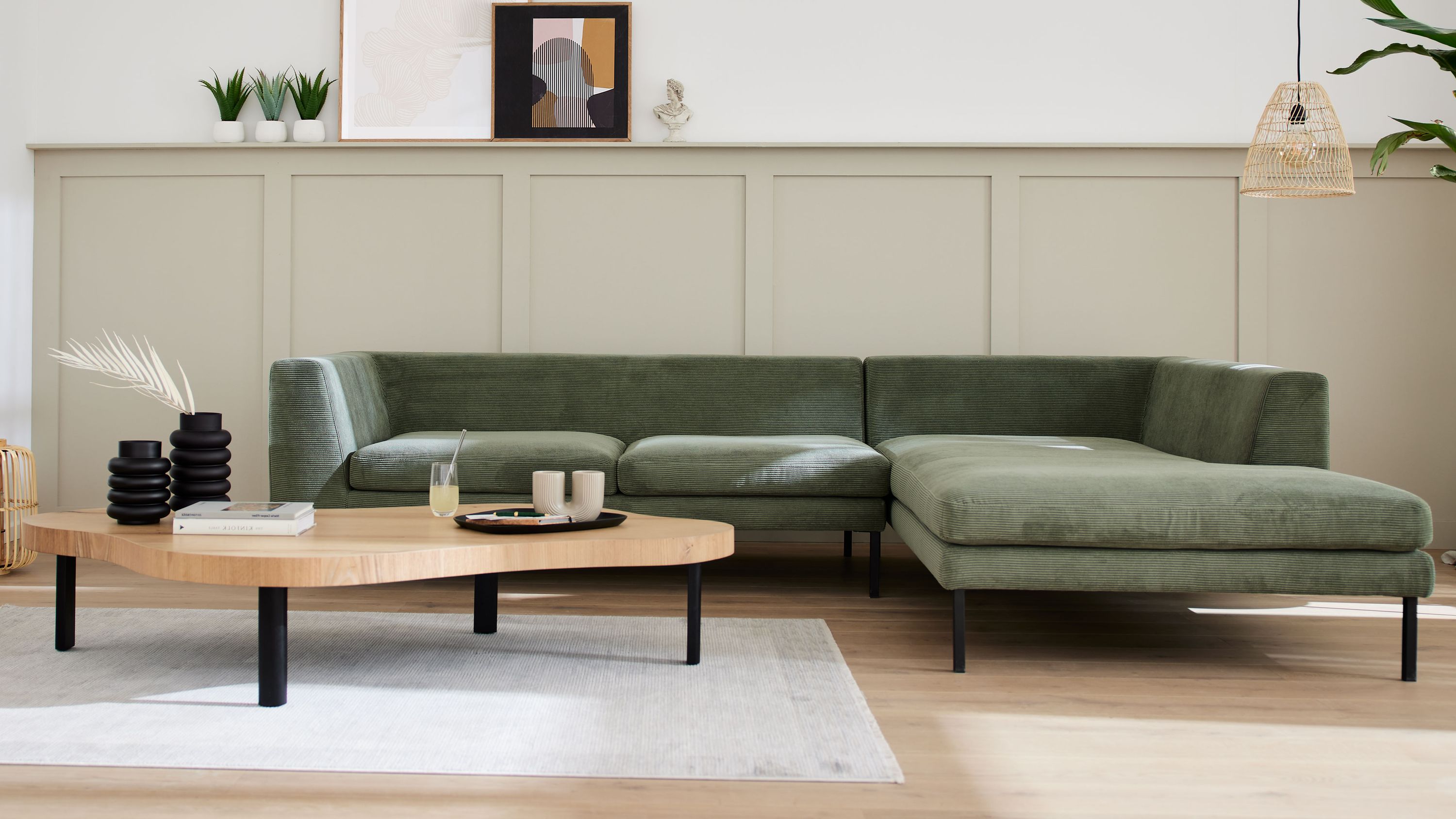 Ecksofa mit olivgrünem Feincordbezug und schwarzen Metallfüßen in modernem Wohnzimmer