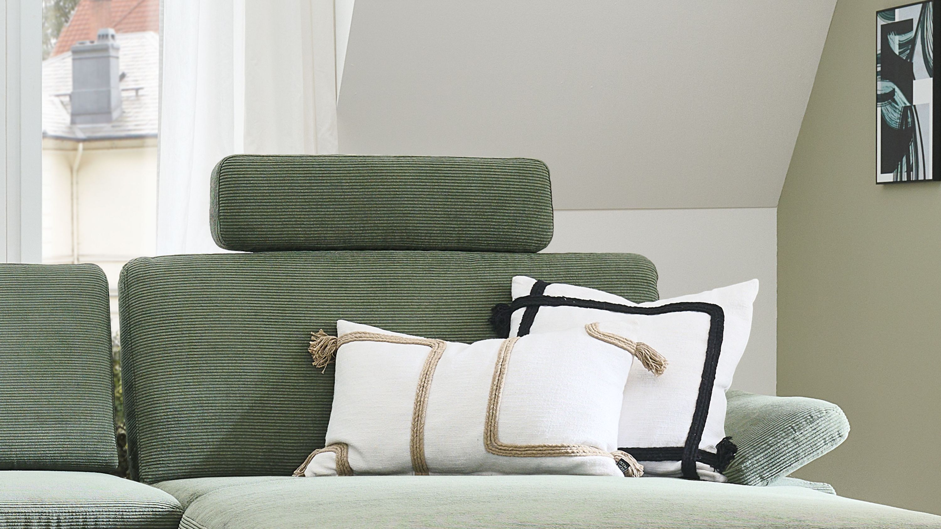 Grünes Sofa mit Kopfstütze und Kissen Grünes Sofa mit Kopfstütze und zwei weißen Kissen mit schwarzen und beigen Akzenten
