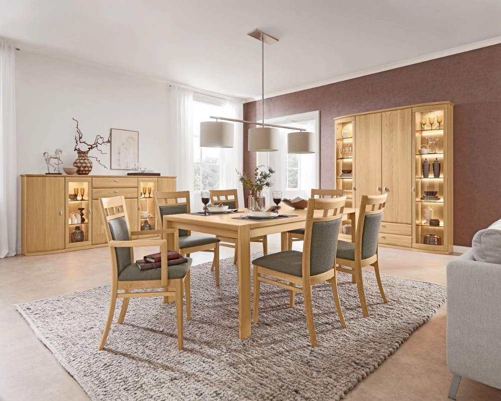 Gemütlicher Essbereich in natürlichem Holzdesign mit stilvoller Beleuchtung. Modernes Esszimmer mit großem Holztisch, sechs Stühlen und Vitrinenschrank auf hellem Teppich.