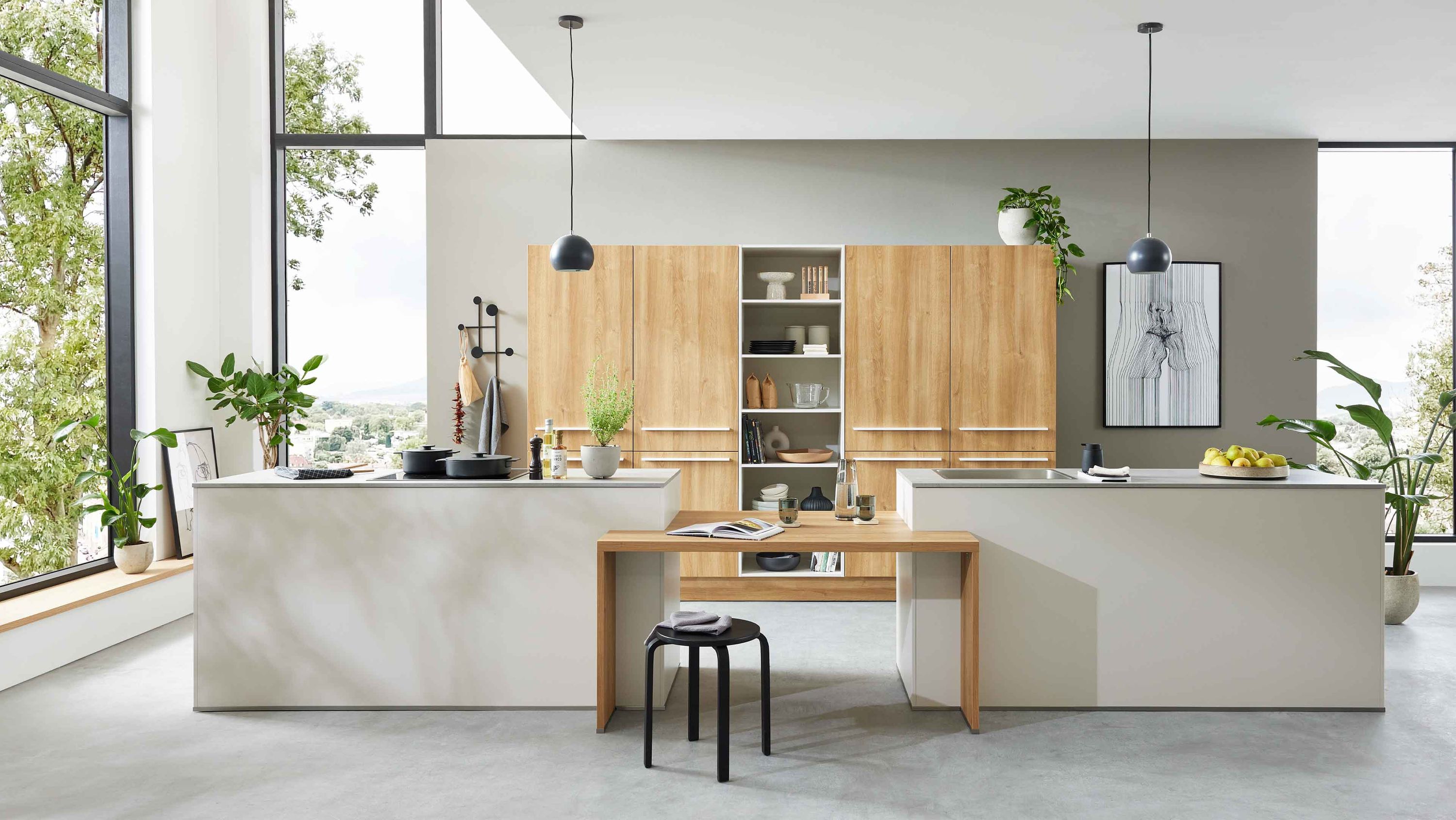 Helle Inselküche mit Holzfronten integriertem Regal Doppelinsel modernen Hängelampen und großen Fensterflächen.