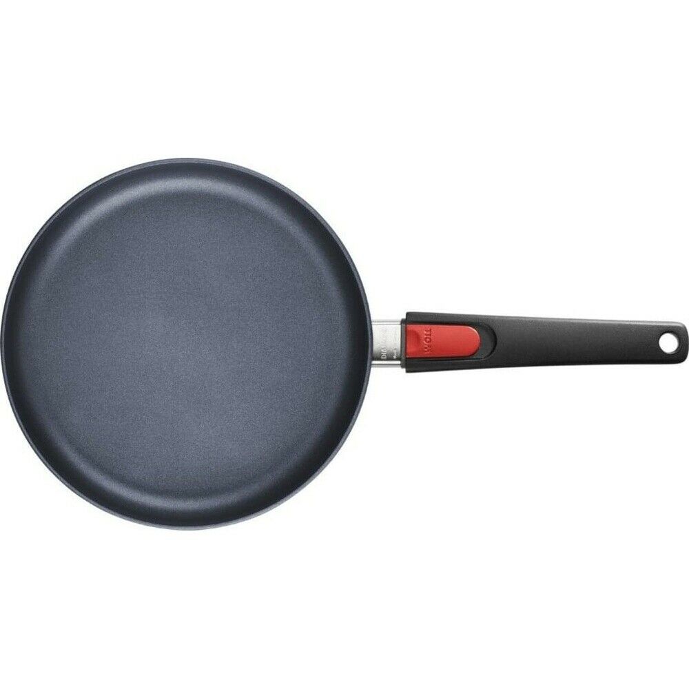 Schwarze Bratpfanne mit rotem Knopf am Griff, von oben fotografiert auf hellem Hintergrund.