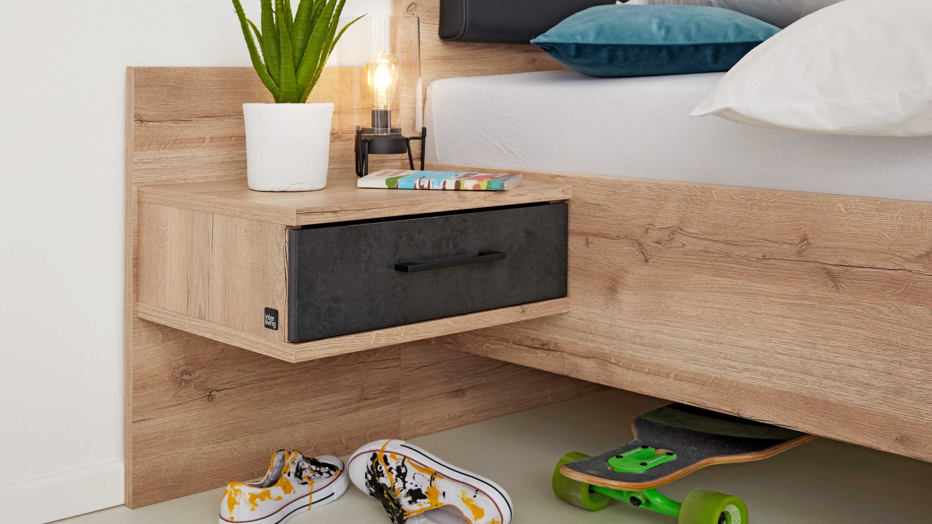 Hängende Konsole mit Schublade in anthrazit und Holzoptik neben einem Bett mit Holzrahmen