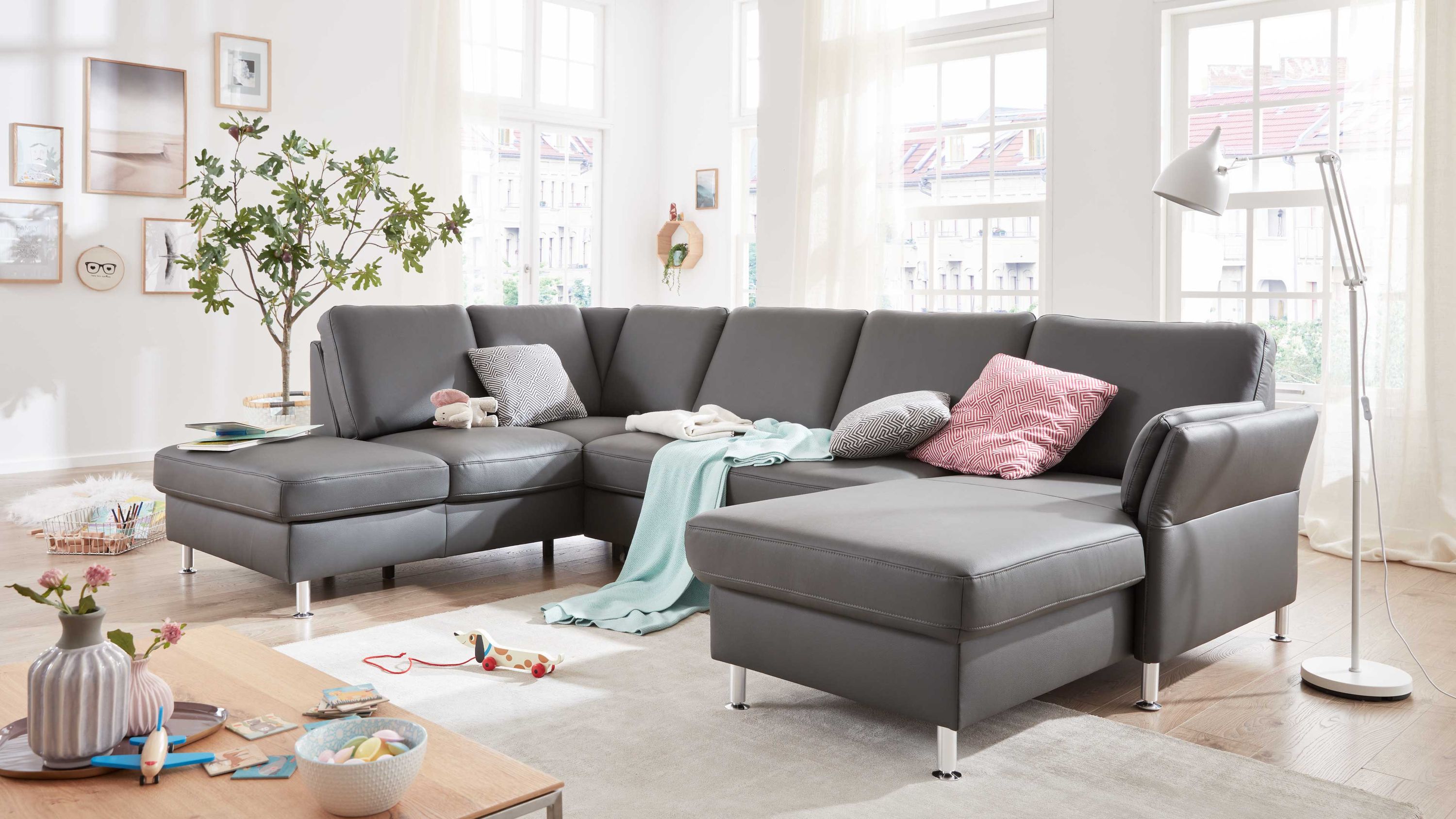 Anthrazitfarbene Wohnlandschaft mit Lederbezug und Metallfüßen Großzügige Wohnlandschaft mit anthrazitfarbenem Lederbezug und Metallfüßen in hellem Wohnzimmer