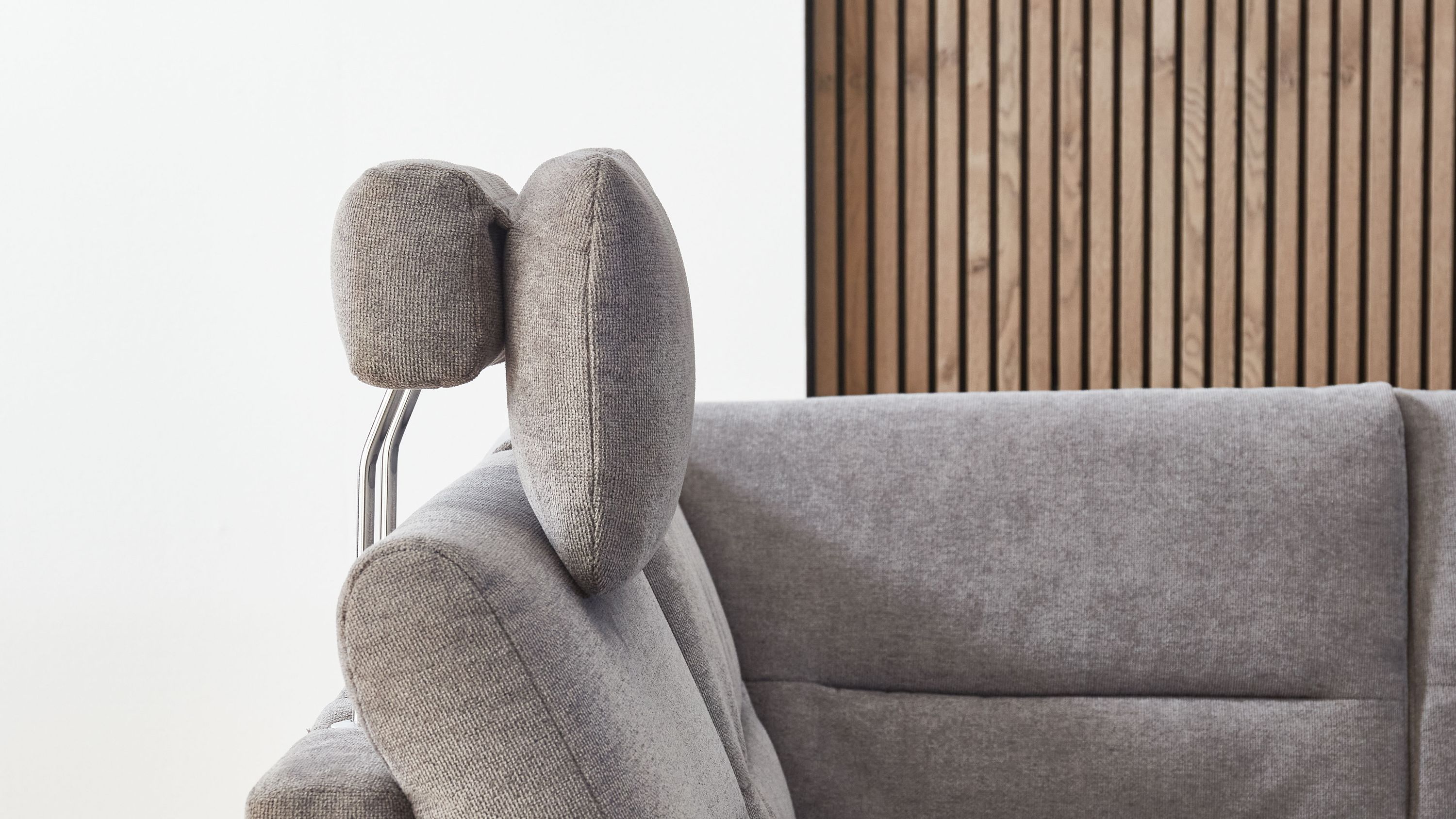 Graue Kopfstütze aus Flachgewebe mit Metallgestell an grauem Polstersofa