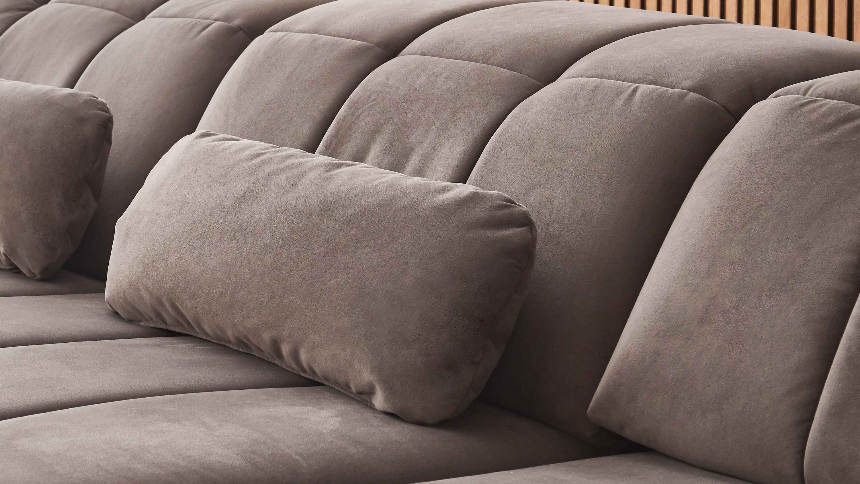 Graues Nierenkissen auf grauem Sofa mit gepolsterten Rückenlehnen