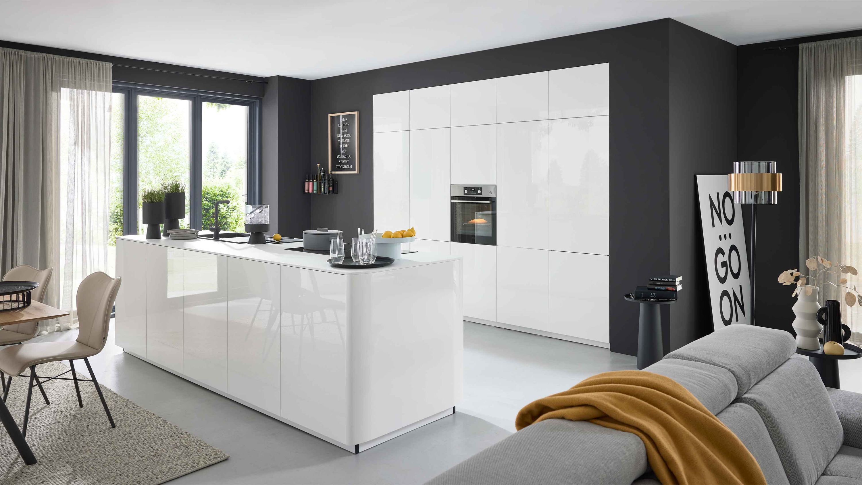 Offene Küche mit weißer Insel Barhockern grauem Sofa gelber Decke Fensterlicht Wandkunst Wohnaccessoires