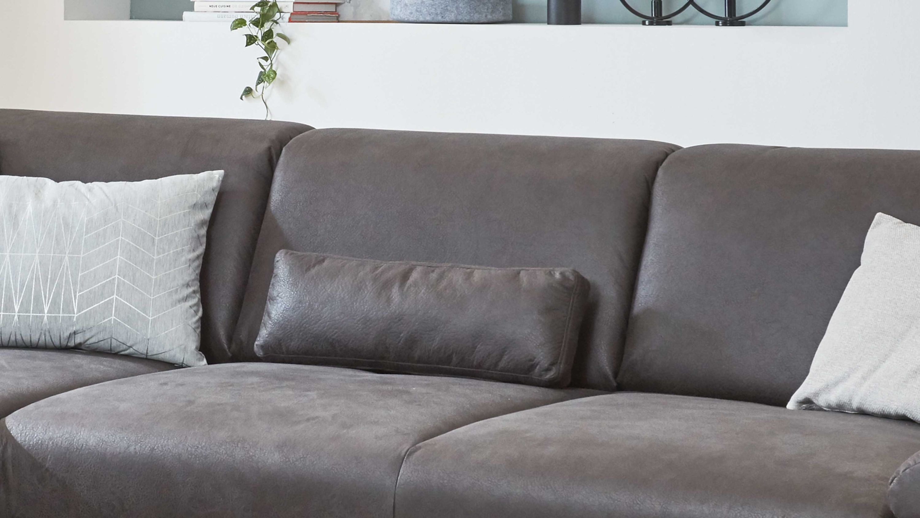 Anthrazitfarbenes Nierenkissen auf dunkelgrauem Sofa mit zwei hellen Kissen