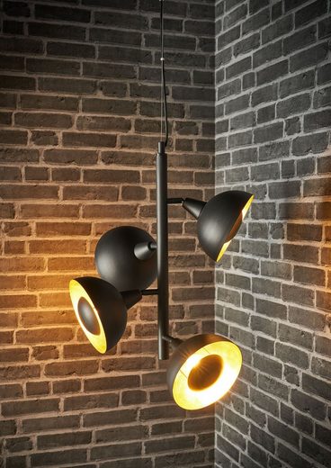 Moderne schwarze Hängelampe mit gelbem Licht Moderne schwarze Hängelampe mit vier Kegellampen, die gelbes Licht auf eine Ziegelwand werfen.