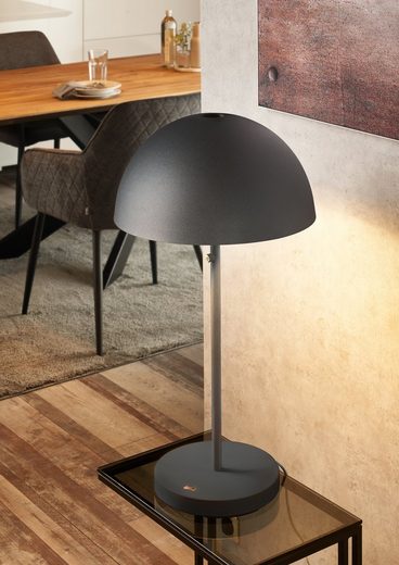 Schwarze Tischlampe mit Kuppelschirm auf Beistelltisch in Raum mit Holzmöbeln, aus seitlicher Perspektive fotografiert