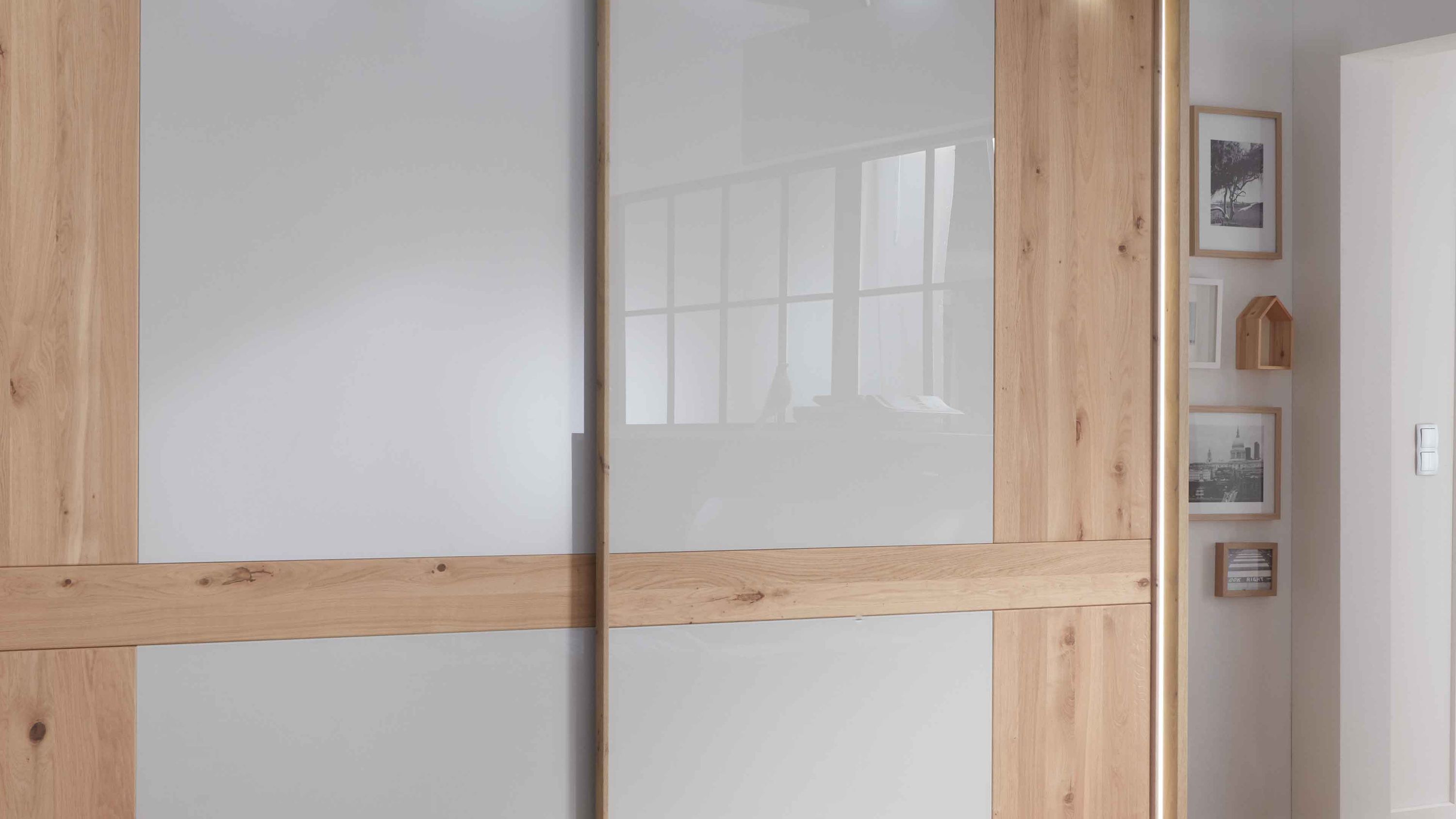 Schwebetürenschrank mit Holzrahmen und weißen Fronten LED-Stollenbeleuchtung am Türrahmen