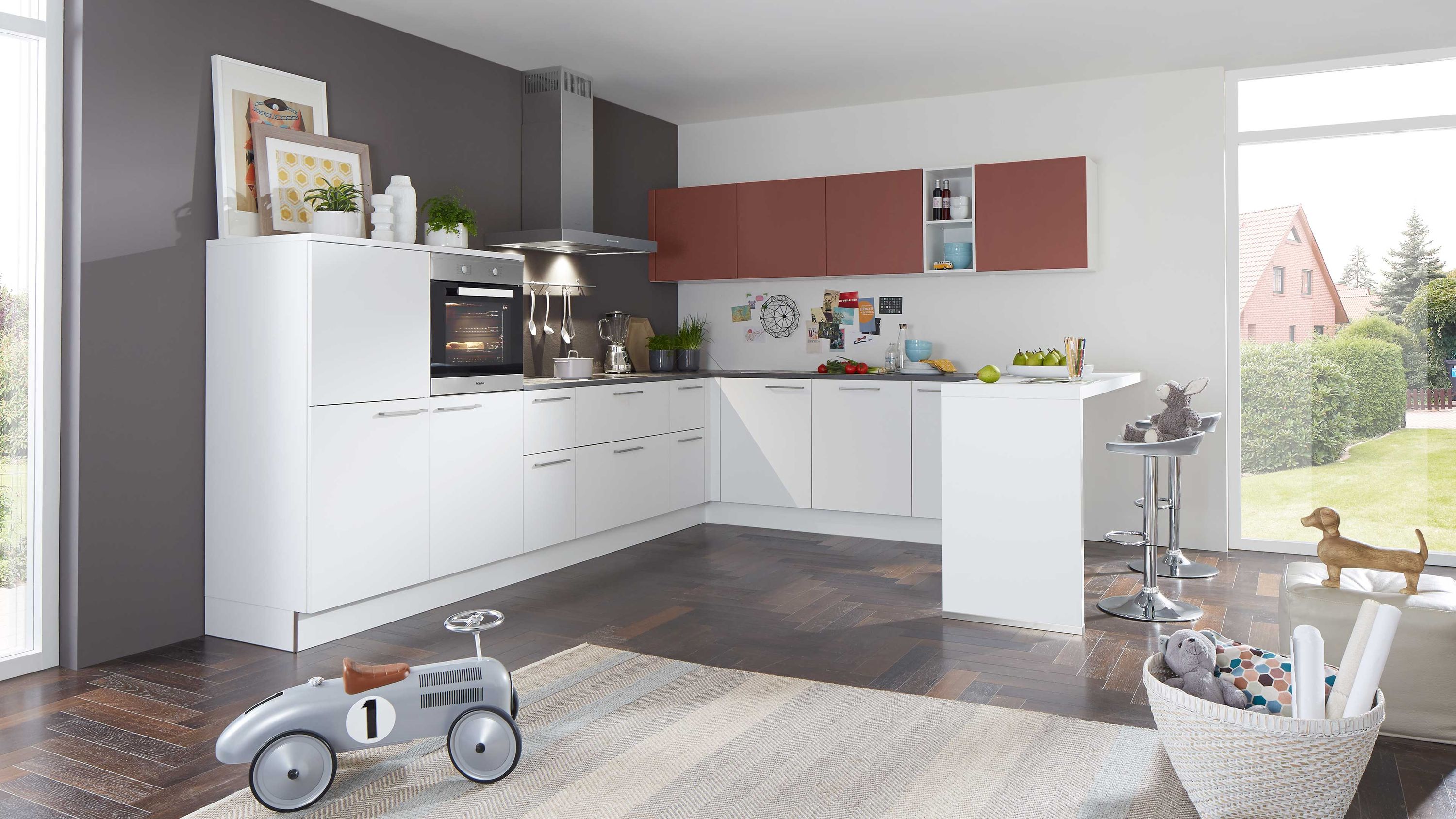 Weiße L-Küche mit roten Hängeschränken und moderner Ausstattung. Moderne L-Küche in Weiß mit roten Hängeschränken dunkler Rückwand und integriertem Backofen.