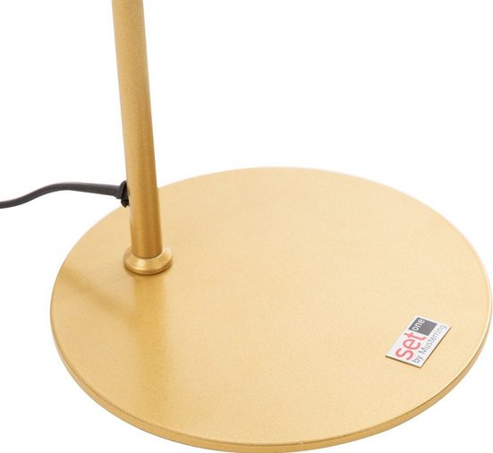Goldener Lampenfuß mit US-Flaggen-Sticker und schwarzem Kabel, aus leicht schräger Perspektive fotografiert.