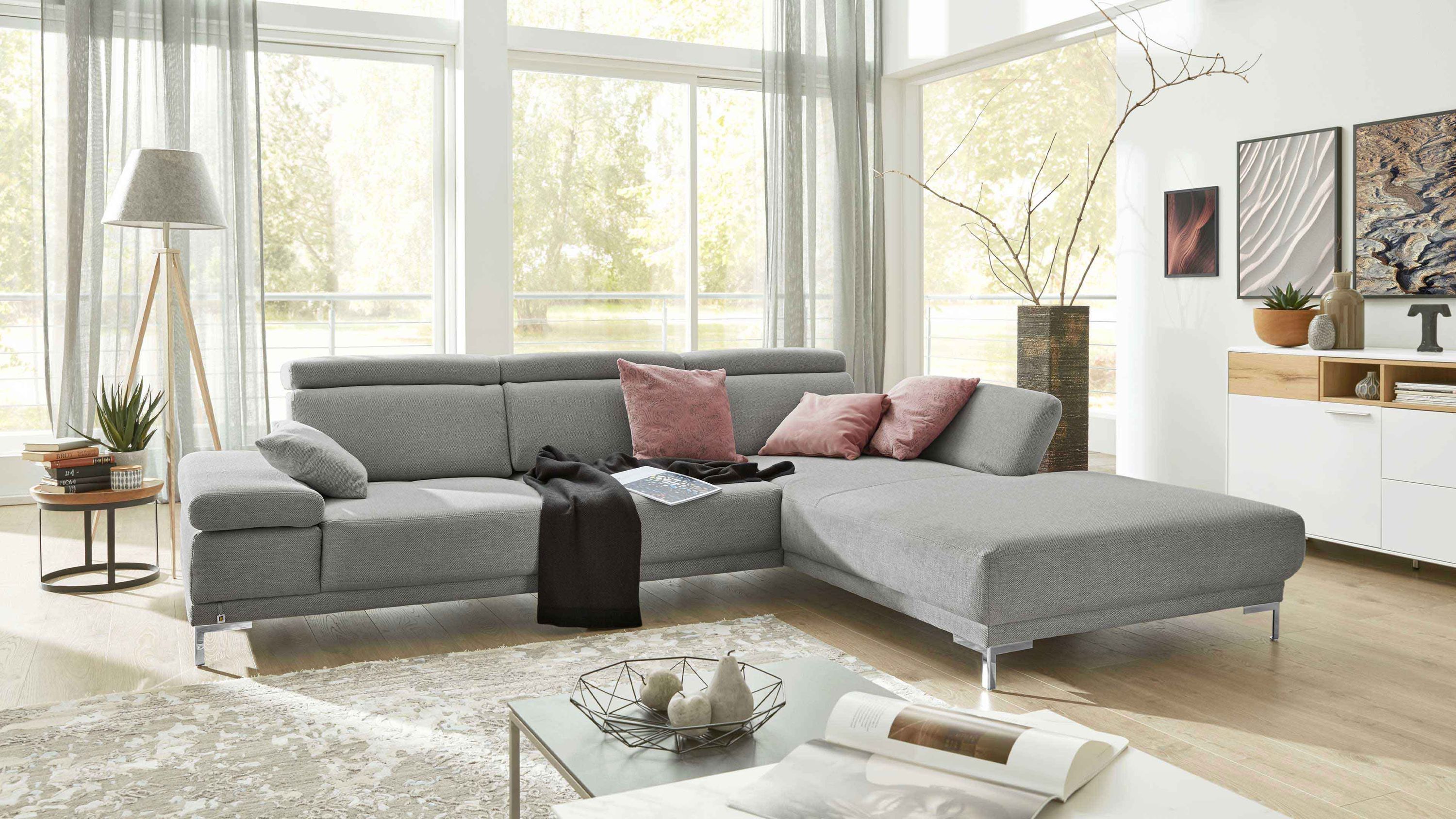 Platinfarbenes Funktions-Ecksofa mit Metallfüßen Ecksofa mit platinfarbenem Bezug verstellbaren Kopfstützen und silberfarbenen Metallfüßen in hellem Wohnzimmer