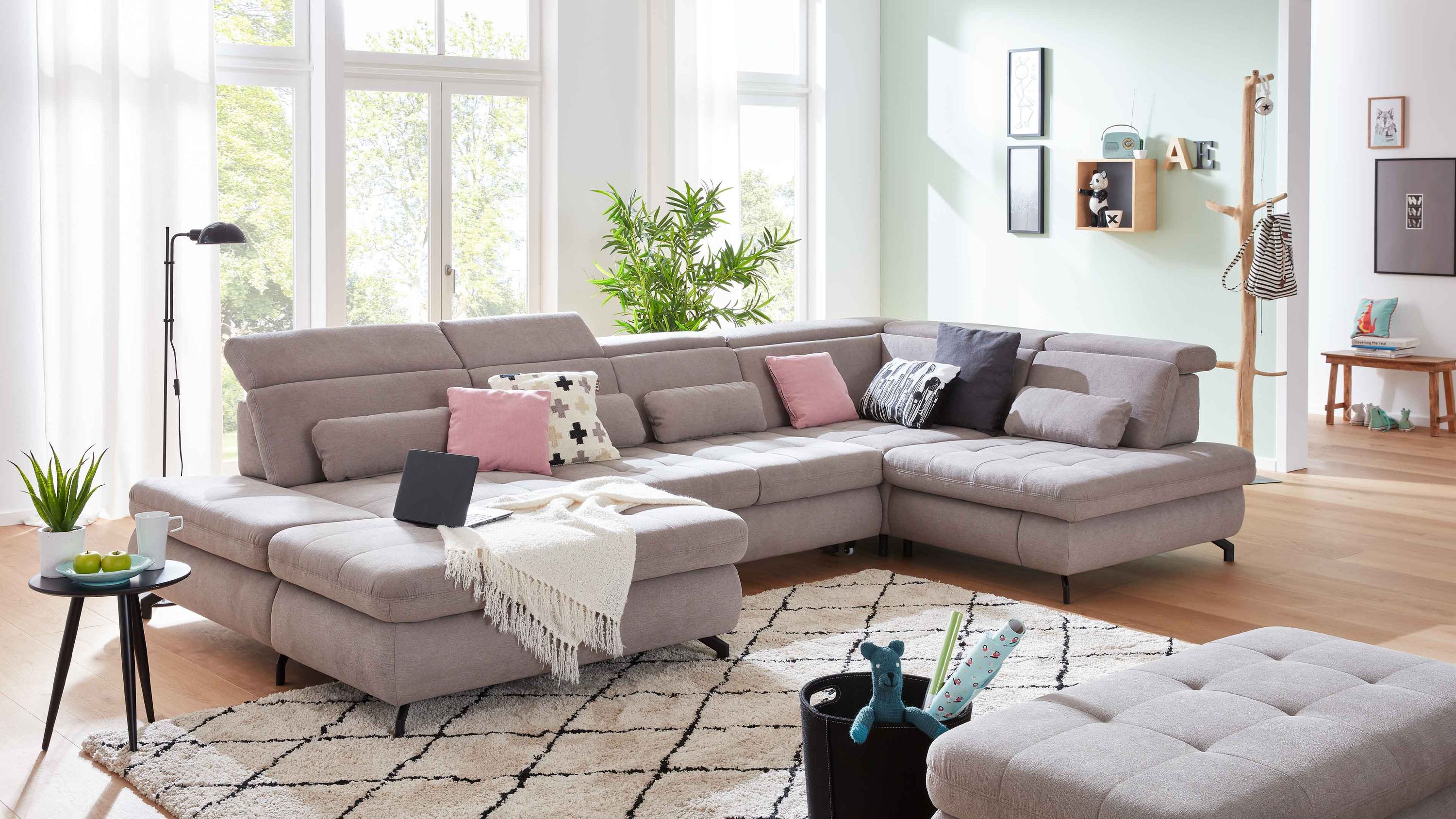 Große Wohnlandschaft mit granitfarbenem Stoffbezug schwarzen Metallfüßen und mehreren Kissen in einem hellen Wohnzimmer