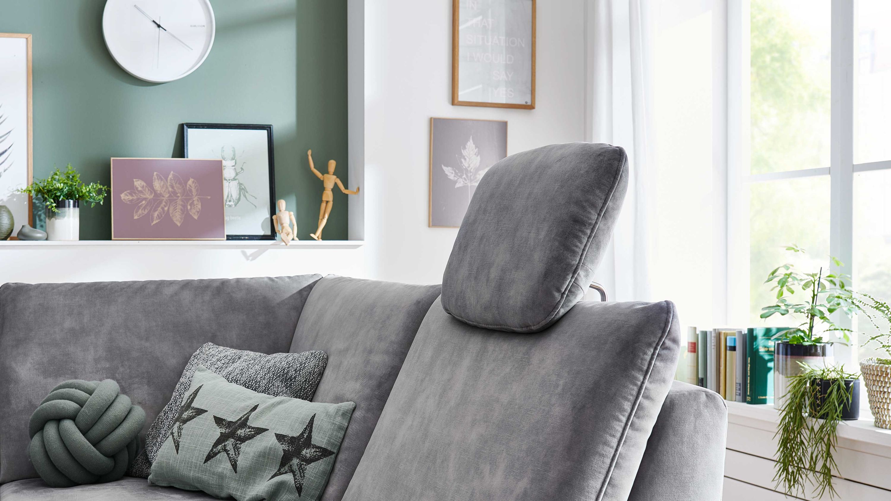 Silberfarbene Kopfstütze in Velours auf grauem Sofa in modernem Wohnzimmer