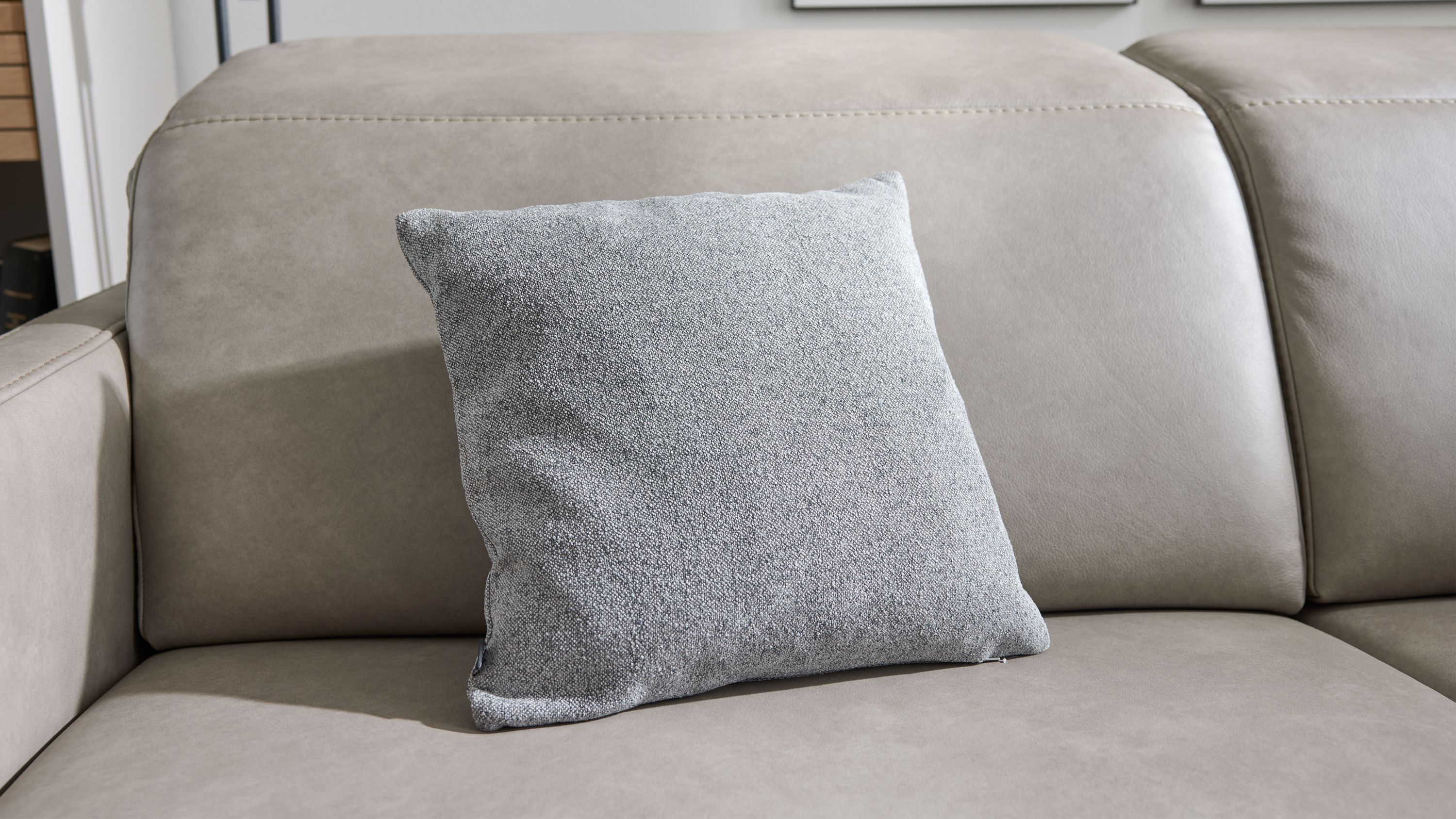 Quadratisches graues Kissen mit strukturierter Oberfläche auf einem hellgrauen Sofa