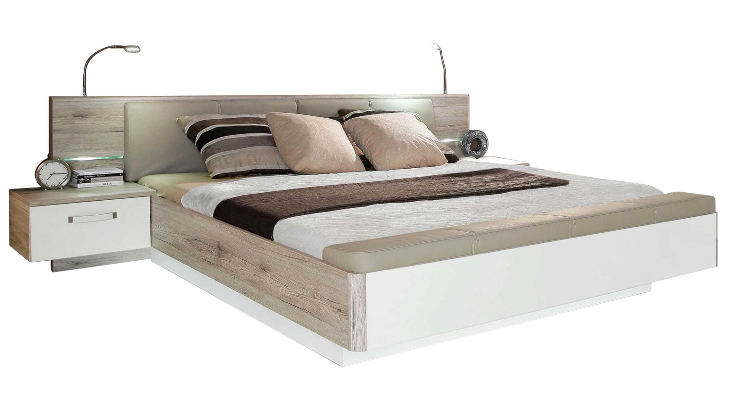 Doppelbett mit sandfarbenem Holz-Kopfteil weißen Fronten zwei Nachttischen und Leselampen
