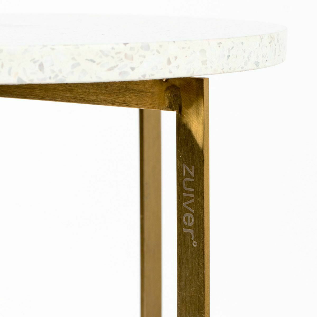 Detailansicht eines goldfarbenen Tischbeins mit zuiver-Gravur  darüber weiße Terrazzo-Platte mit feiner Musterung