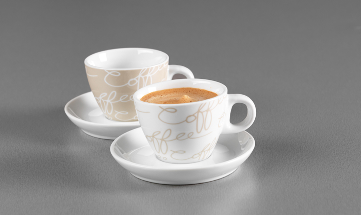 Zwei Espressotassen mit Untertassen in Weiß und Creme mit Schriftzug auf grauem Hintergrund