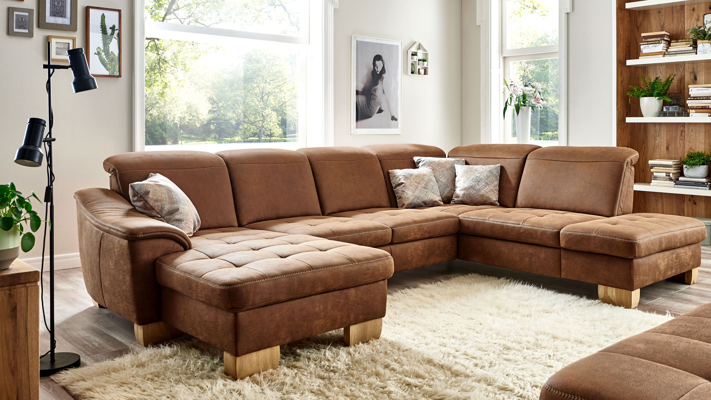 Ecksofa in U-Form mit Holzfüßen und tabacfarbenem Bezug Ecksofa in U-Form mit tabacfarbenem Bezug und hellen Holzfüßen mit Kissen auf einem Teppich