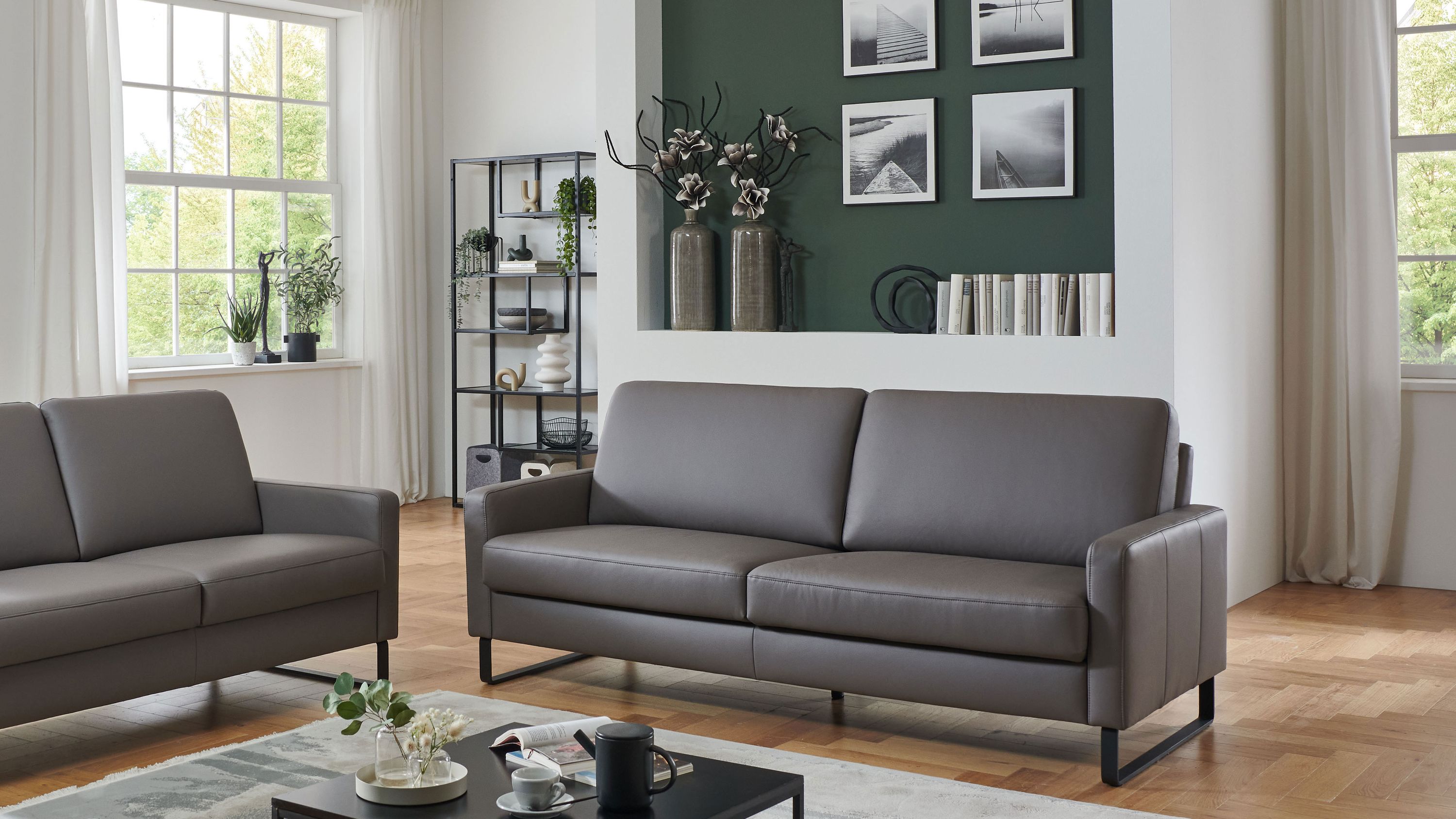 Zweisitziges Sofa in graubrauner Farbe Zweisitziges Sofa mit glatten Polstern und Armlehnen in graubrauner Farbe in modernem Wohnzimmer