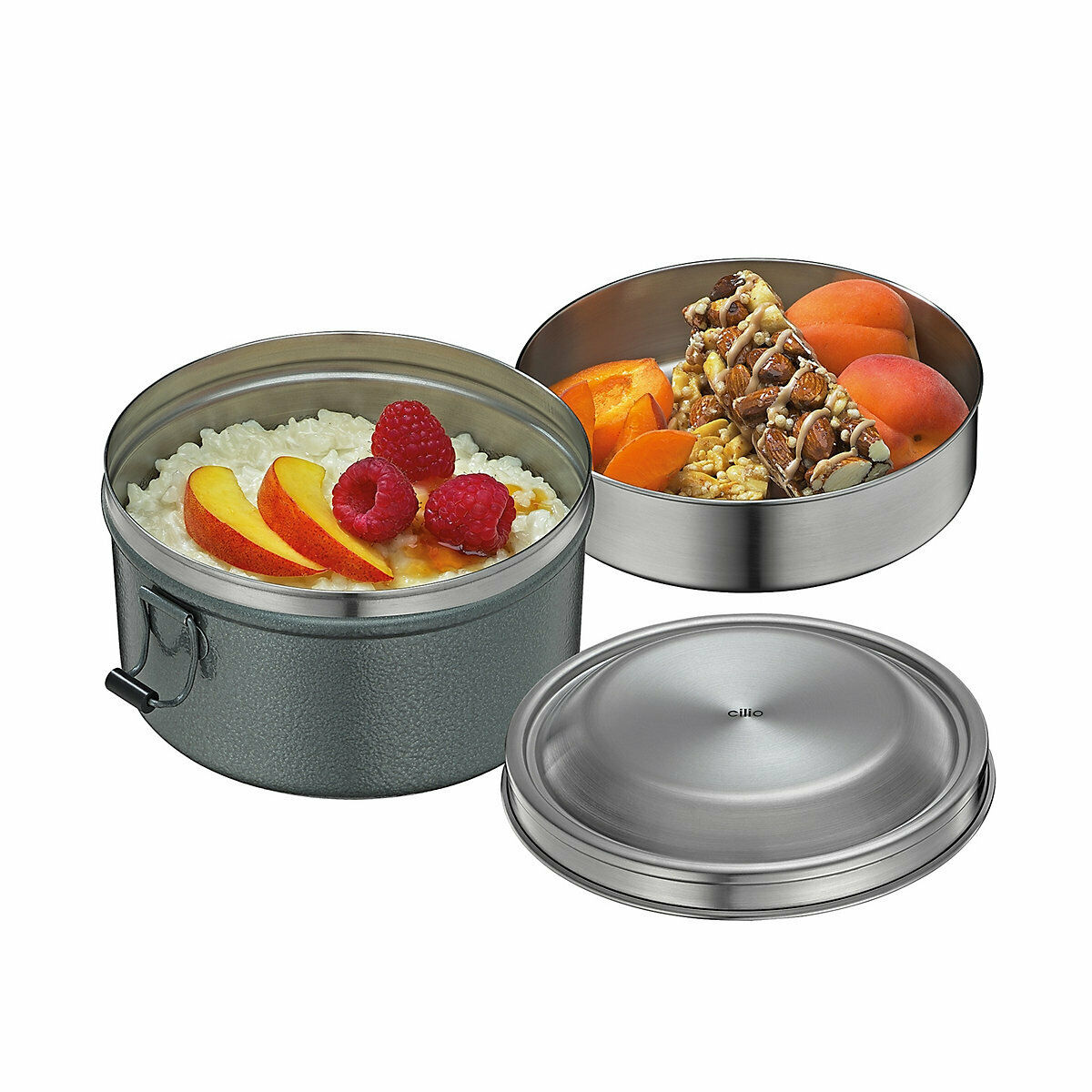 Zweistöckige Lunchbox mit Joghurt  Äpfeln  Himbeeren unten und Aprikosen  Nüssen oben  Deckel daneben liegend