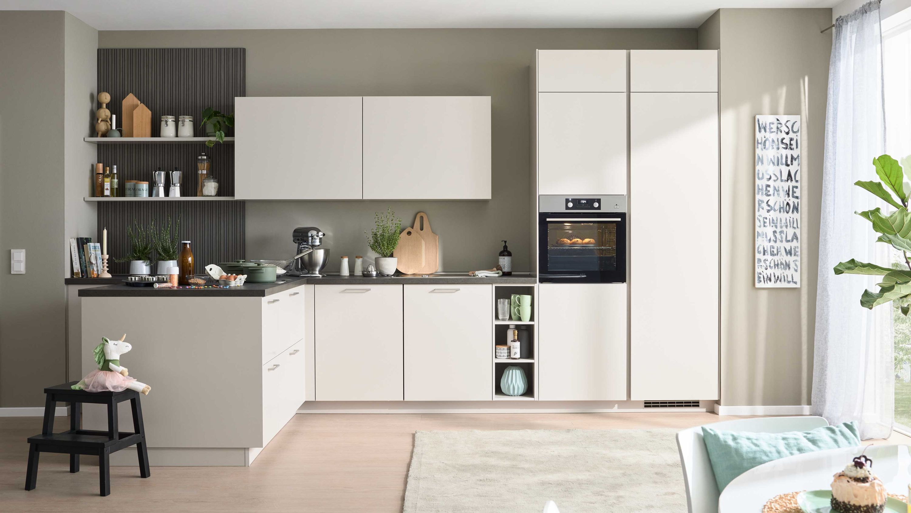 Helle Designerküche mit Tageslicht und modernen Einbauten Moderne Küche mit hellen Fronten Einbauofen Hockern Pflanzen Tageslicht durch Fenster mit transparenten Vorhängen