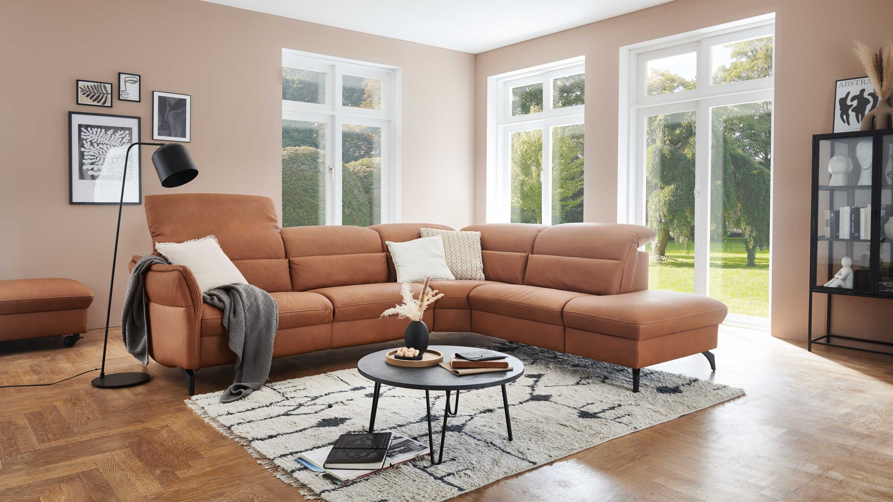 Ecksofa mit verstellbaren Rückenlehnen und honigfarbenem Leder in hellem Wohnzimmer mit Teppich und Beistelltisch