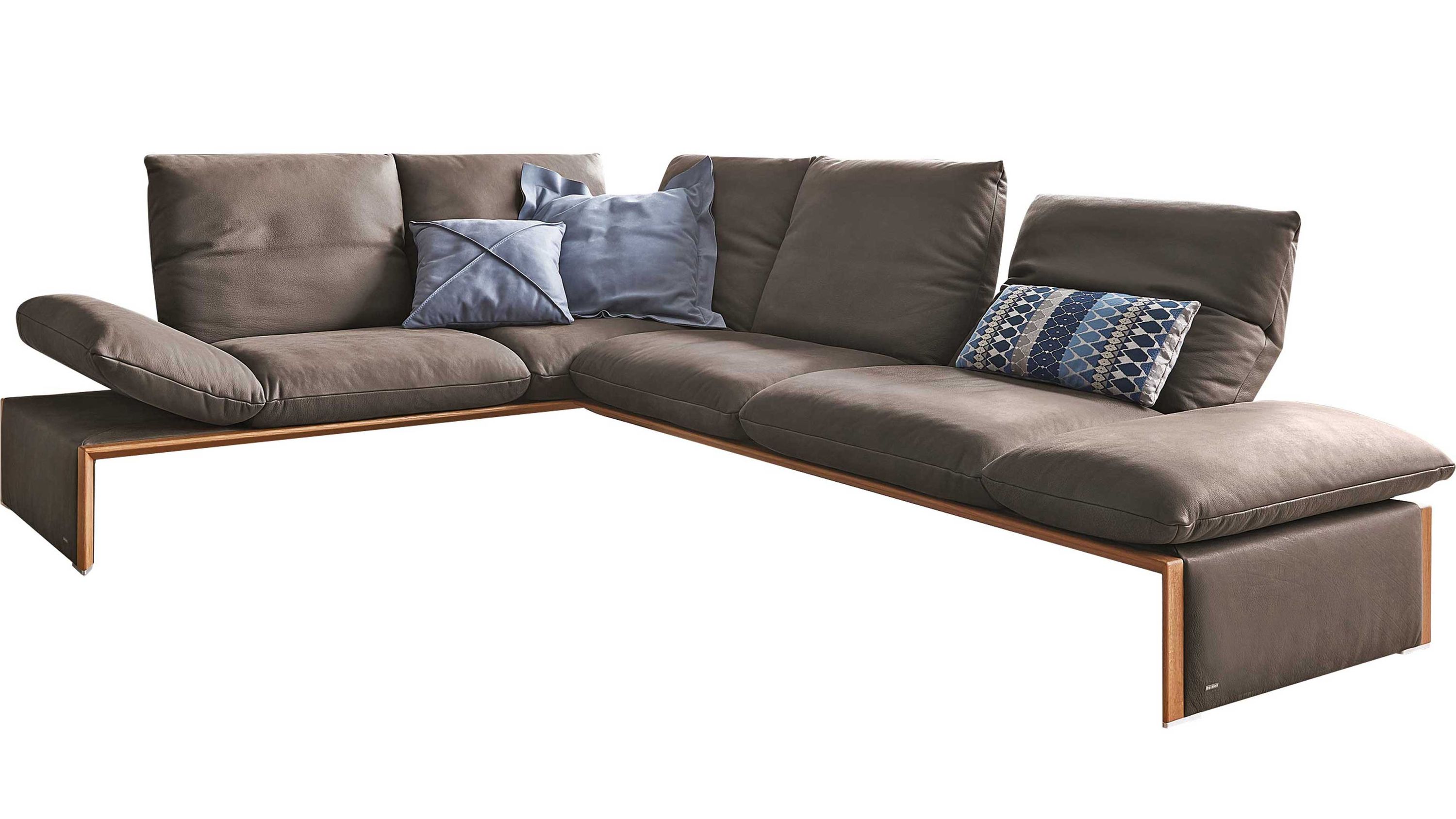 Ecksofa mit dunkelbraunem Lederbezug und Holzakzenten drei Rückenkissen und zwei blauen Zierkissen