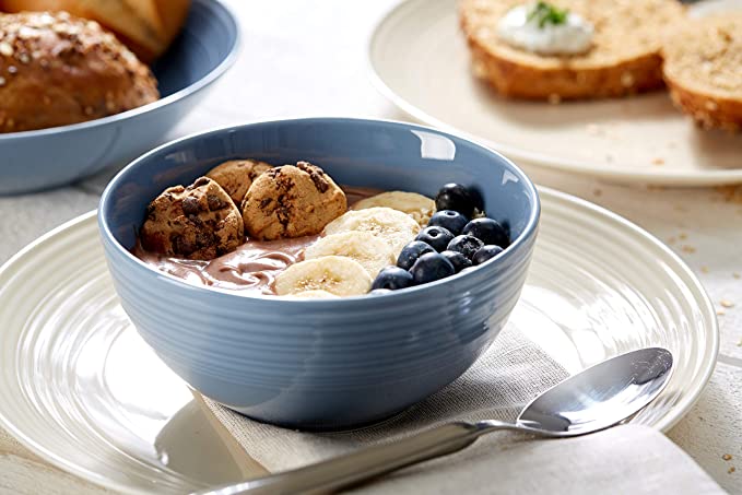Blauer Frühstücksteller mit Obstschale Blauer Frühstücksteller mit Obstschale  Bananen  Blaubeeren und Gebäck im Hintergrund