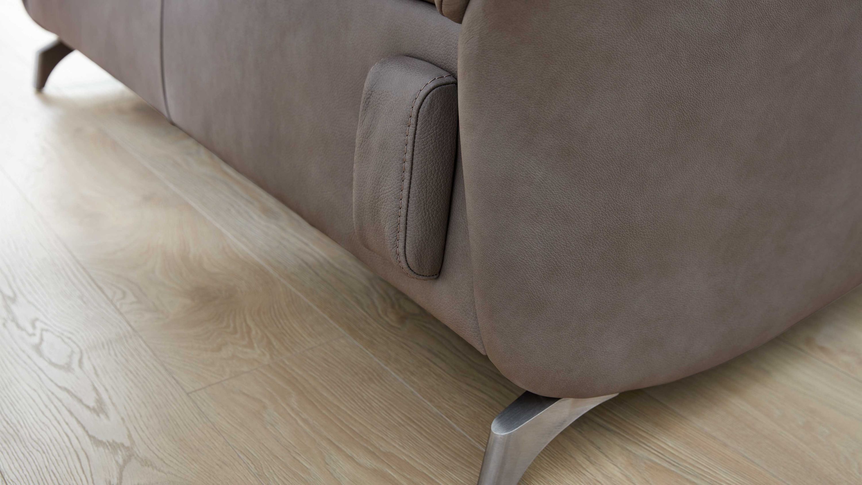 Nahaufnahme eines titanfarbenen Sofas mit abgerundeter Ecke und Metallfuß auf hellem Holzboden